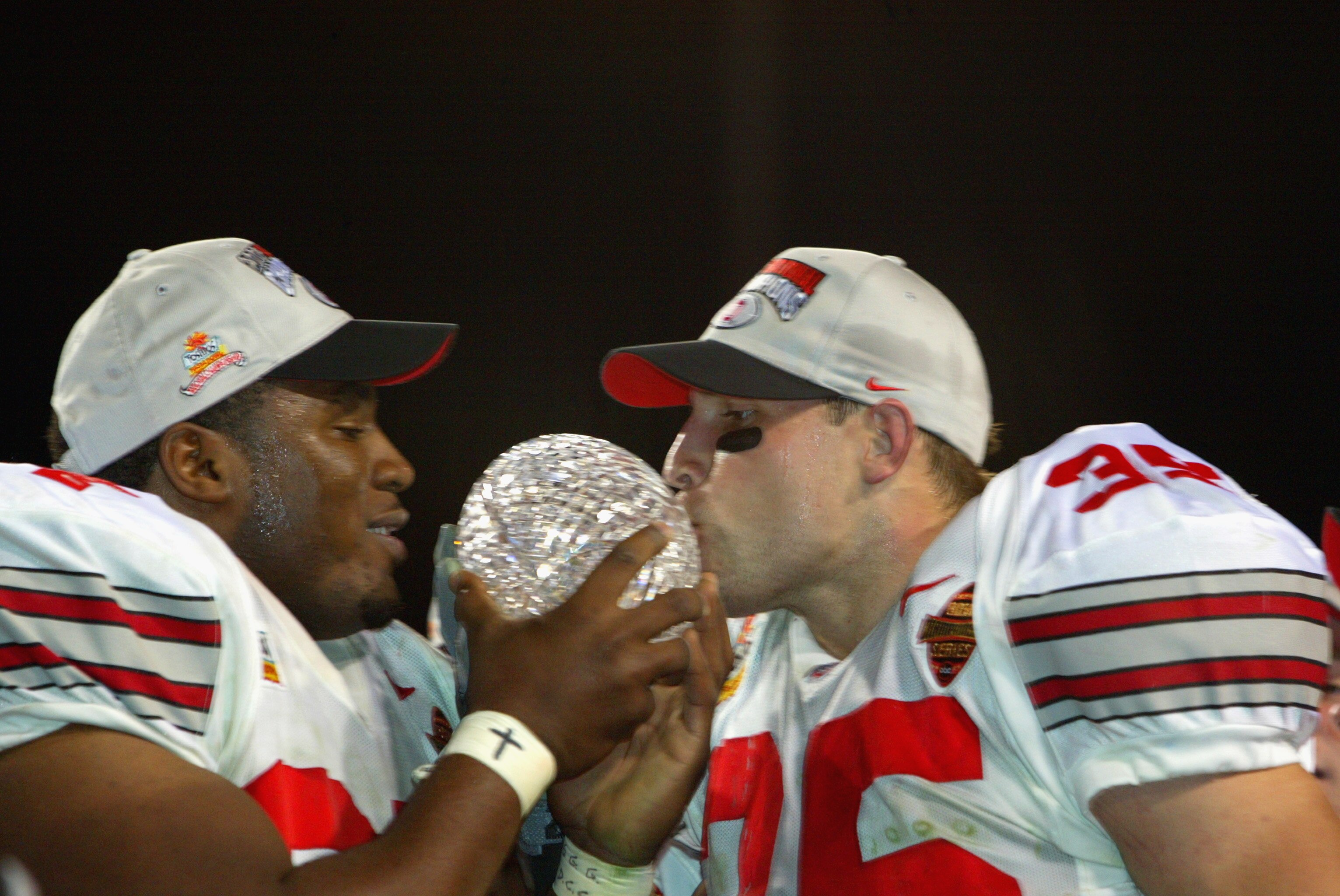 TEMPE, AZ - JANUARY 3: Kenny Peterson #97 (l) and Matt Wilheim #35 of the Ohio State Buckeyes celebrate with the National Championship trophy after defeating the Miami Hurricanes 31-24 in double overtime the Tostitos Fiesta Bowl on January 3, 2003 at Sun TEMPE, AZ - JANUARY 3: Kenny Peterson #97 (l) and Matt Wilheim #35 of the Ohio State Buckeyes celebrate with the National Championship trophy after defeating the Miami Hurricanes 31-24 in double overtime the Tostitos Fiesta Bowl on January 3, 2003 at Sun