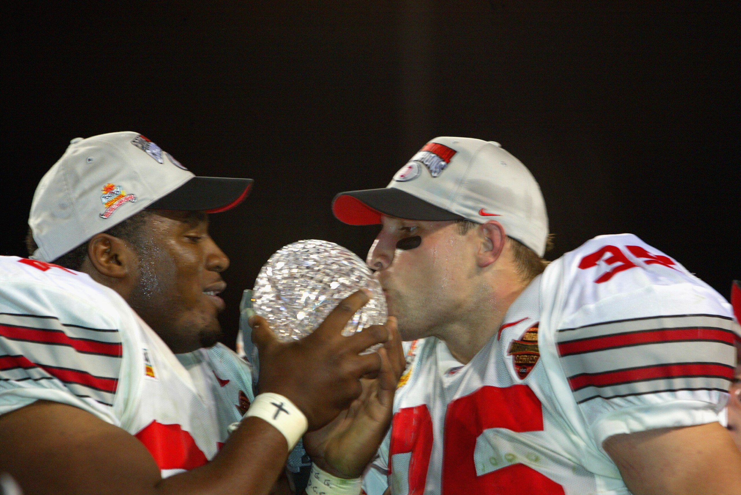 TEMPE, AZ - JANUARY 3:  Kenny Peterson #97 (l) and Matt Wilheim #35 of the Ohio State Buckeyes celebrate with the National Championship trophy after defeating the Miami Hurricanes 31-24 in double overtime the Tostitos Fiesta Bowl on January 3, 2003 at Sun