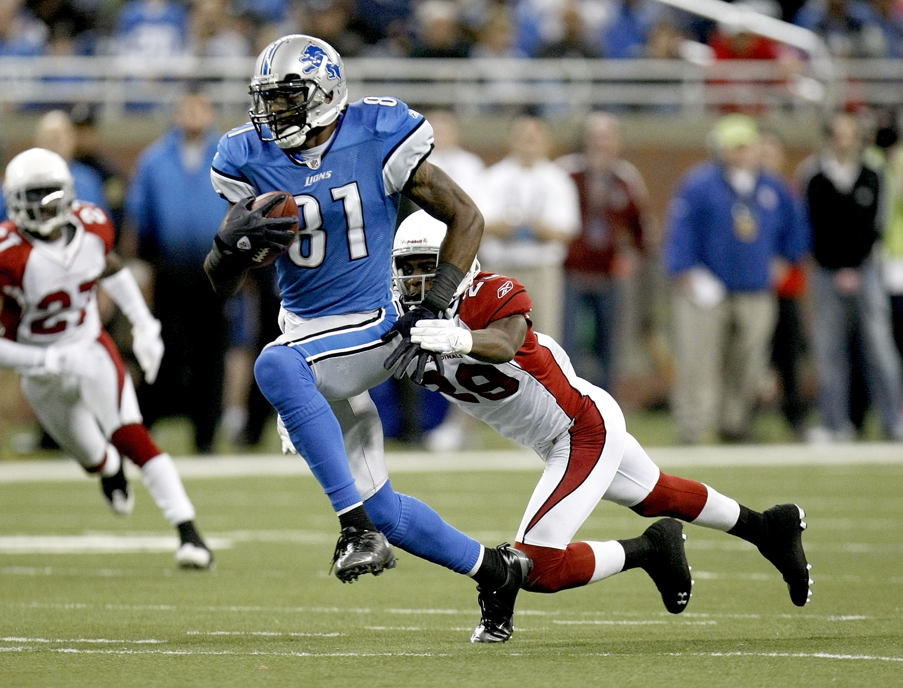 DETROIT - DECEMBER 20:  Calvin Johnson #81 of the Detroit Lions runs past the tackle of Greg Toler #28 of the Arizona Cardinals on December 20, 2009 at Ford Field in Detroit, Michigan. Arizona won the game 31-24.  (Photo by Gregory Shamus/Getty Images)