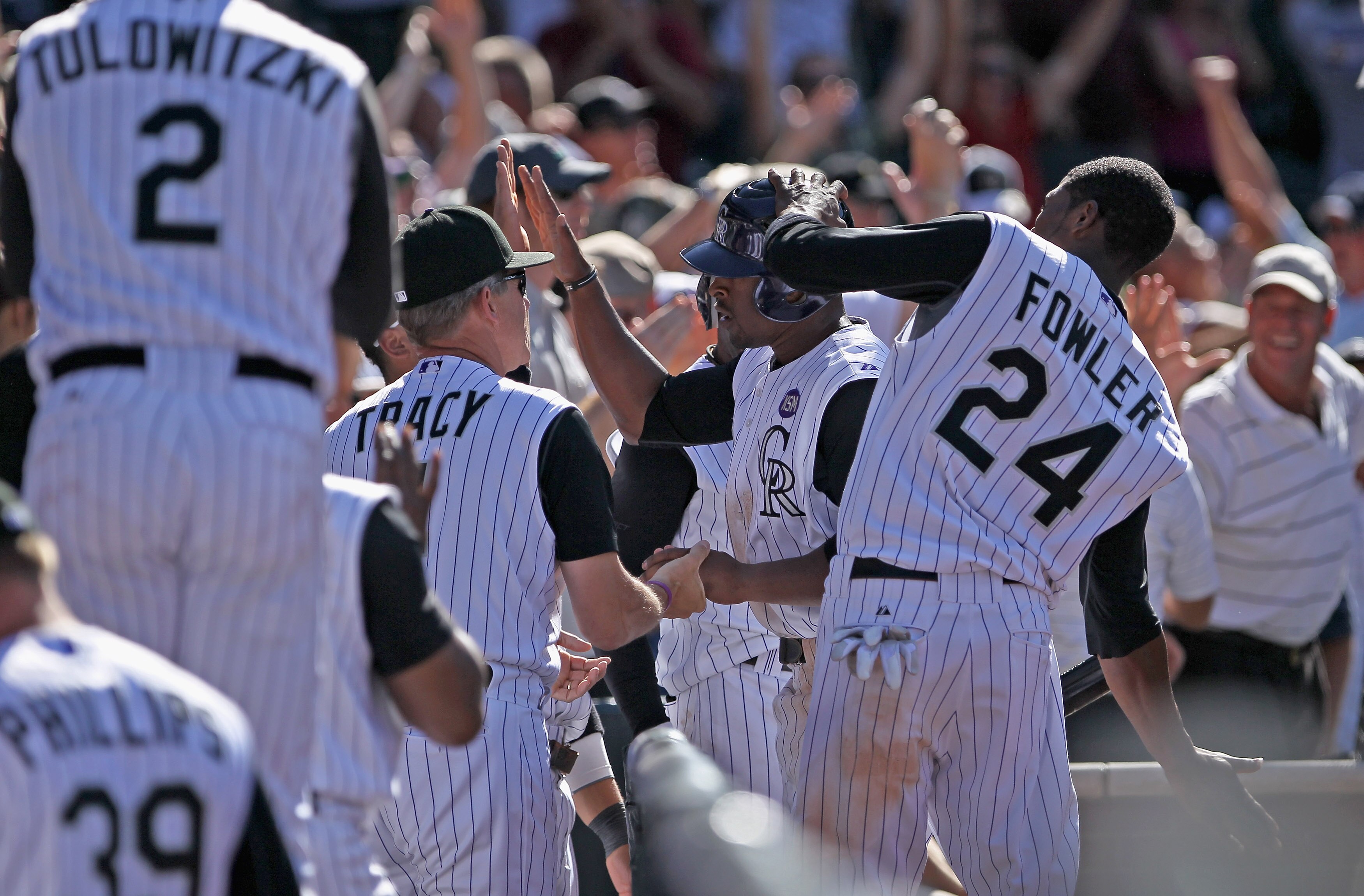 DENVER - SEPTEMBER 09:  Chris Nelson #10 of the Colorado Rockies is welcomed back to the dugout by Dexter Fowler #24 and manager Jim Tracy #4 after stealing home to score the game winning run against pitcher Nick Masset of the Cincinnati Reds in the eight