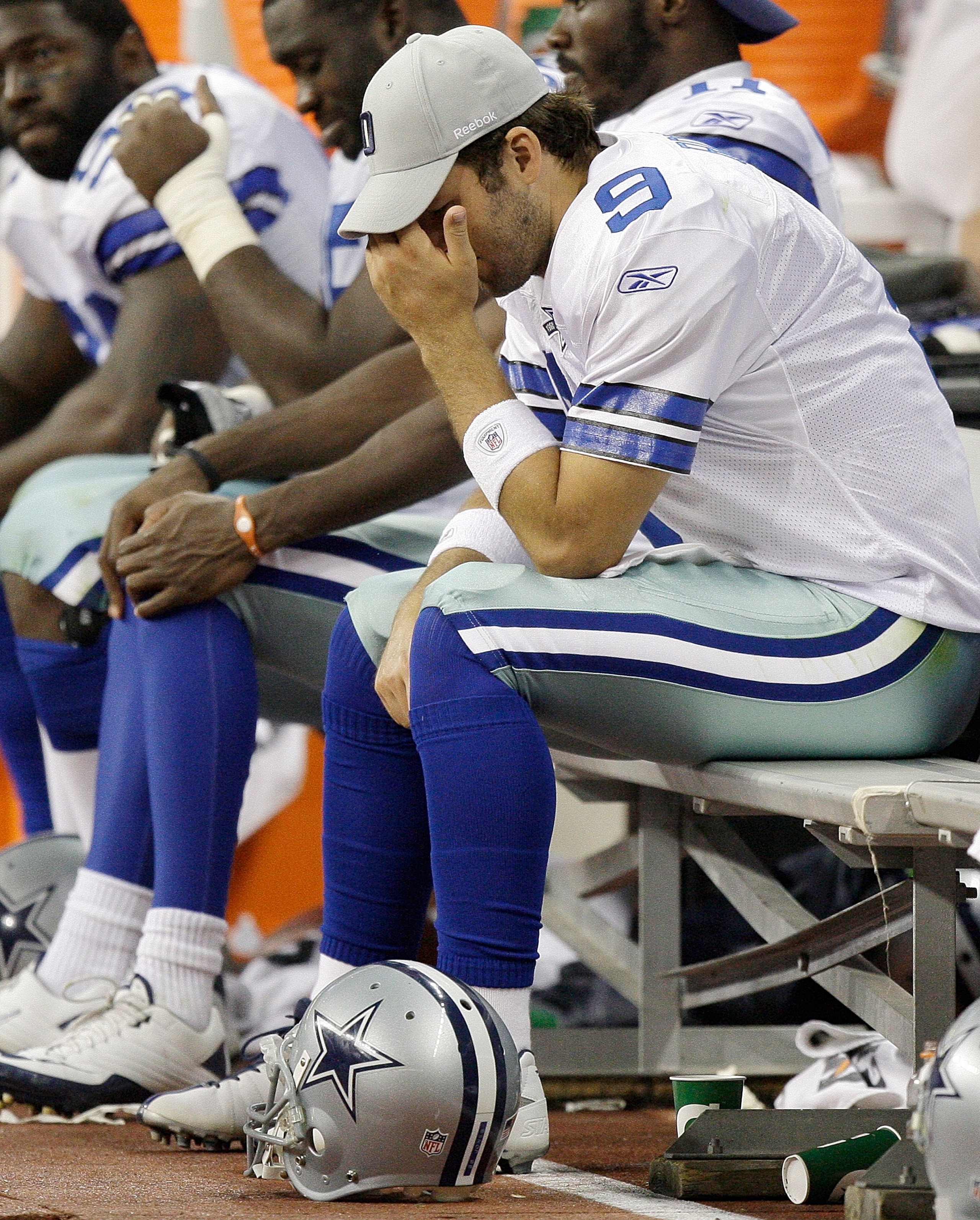 HOUSTON - AUGUST 28: Quarterback Tony Romo #9 of the Dallas Cowboys holds his head as he sits on the bench in the fourth quarter during a game against the Houston Texans at Reliant Stadium on August 28, 2010 in Houston, Texas. Houston won 23-7. (Photo by 