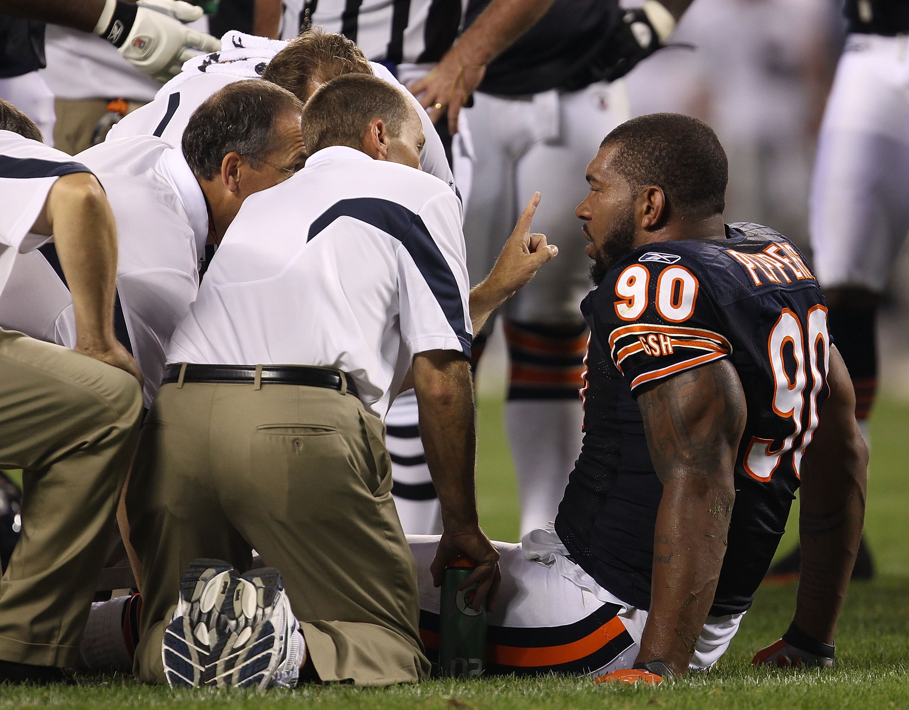 CHICAGO - AUGUST 21: Julius Peppers #90 of the Chicago Bears is attended to by trainers after an injury against the Oakland Raiders during a preseason game at Soldier Field on August 21, 2010 in Chicago, Illinois. The Radiers defeated the Bears 32-17. (Ph