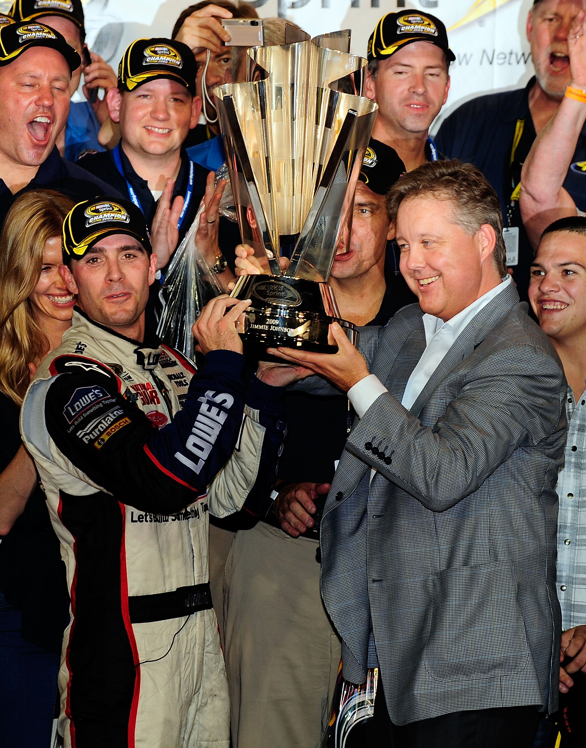 HOMESTEAD, FL - NOVEMBER 22:  Jimmie Johnson (L), driver of the #48 Lowe's Chevrolet, and NASCAR Chairman and CEO Brian France hoist the trophy after winning the NASCAR Sprint Cup Series Championship after finishing in fifth place in the Ford 400 at Homes