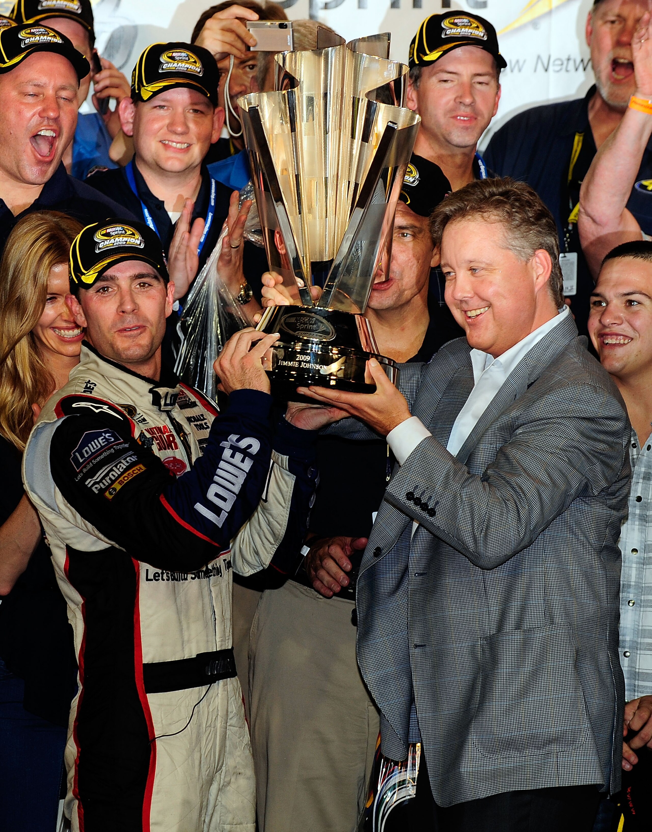 HOMESTEAD, FL - NOVEMBER 22:  Jimmie Johnson (L), driver of the #48 Lowe's Chevrolet, and NASCAR Chairman and CEO Brian France hoist the trophy after winning the NASCAR Sprint Cup Series Championship after finishing in fifth place in the Ford 400 at Homes
