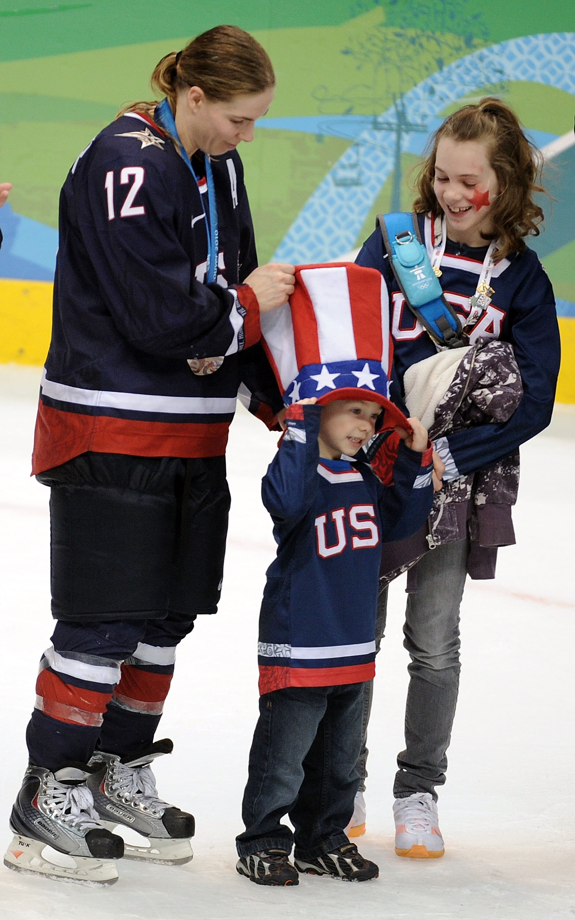 VANCOUVER, BC - FEBRUARY 25:  Jenny Potter #12 of the United States is joined by her children as she received her silver medal  in the medal ceremony following the ice hockey women's gold medal game between Canada and USA on day 14 of the Vancouver 2010 W