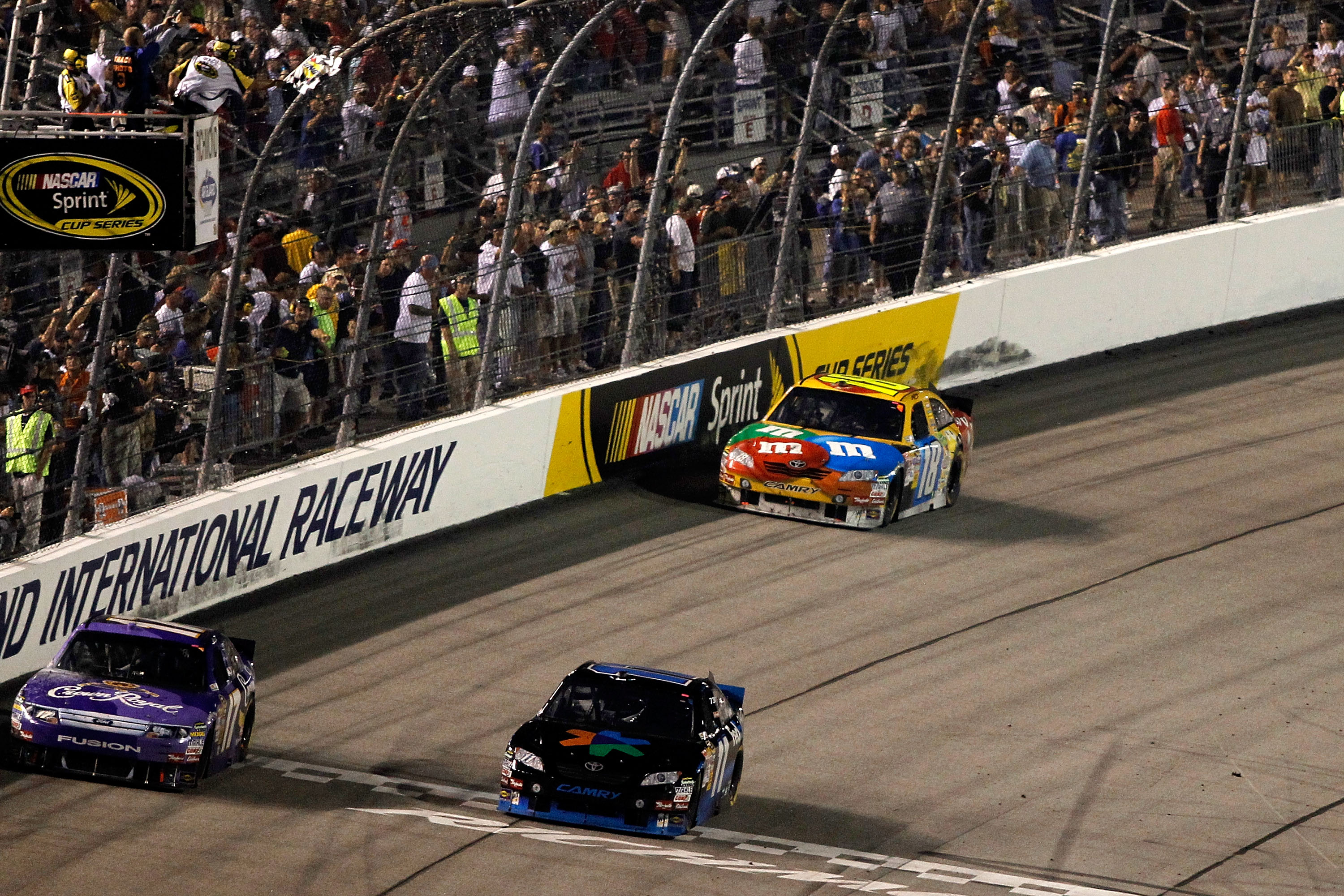RICHMOND, VA - SEPTEMBER 11:  Denny Hamlin (center), driver of the #11 FedEx Office Toyota, crosses the finish line ahead of teammate Kyle Busch (right), driver of the #18 M&Ms Toyota, and Matt Kenseth (left), driver of the #17 Crown Royal Ford (1 lap dow
