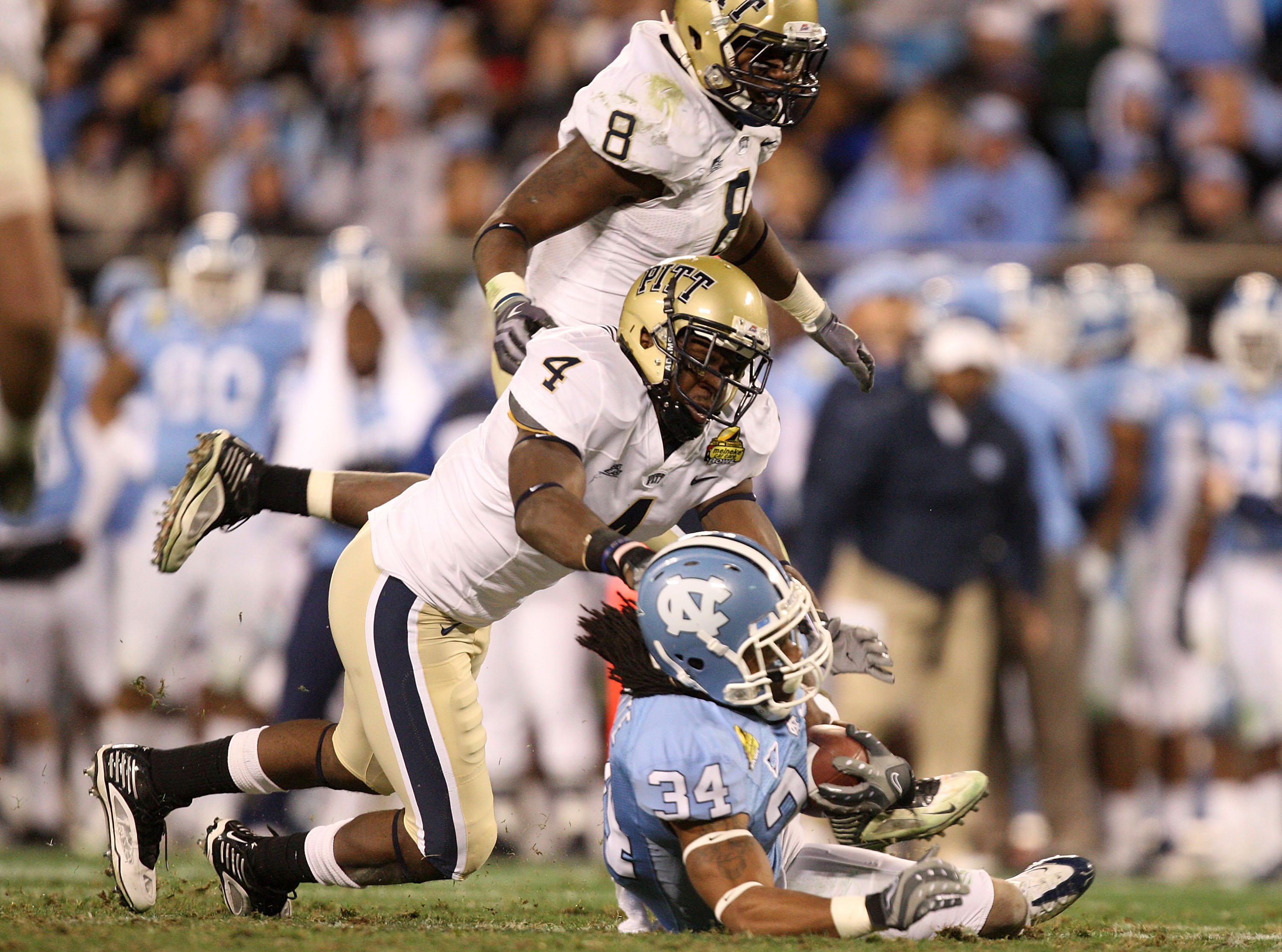 CHARLOTTE, NC - DECEMBER 26:  Teammates Adam Gunn #8 and Elijah Fields #4 of the Pittsburgh Panthers tackle Johnny White #34 of the North Carolina Tar Heels during their game on December 26, 2009 in Charlotte, North Carolina.  (Photo by Streeter Lecka/Get