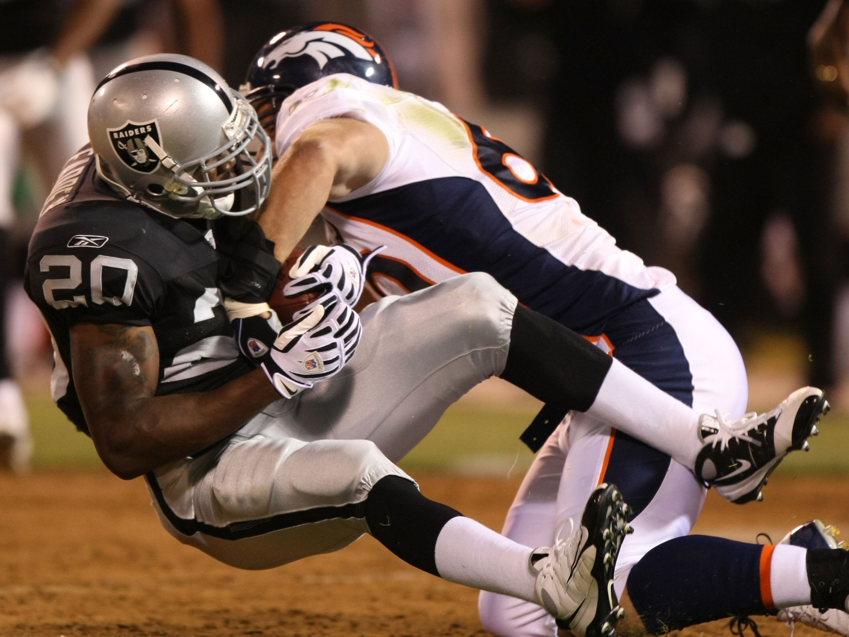 OAKLAND, CA - SEPTEMBER 08: John Engelberger #60 of the Denver Broncos tackles Darren McFadden #20 of the Oakland Raiders during an NFL game at McAfee Coliseum on September 8, 2008 in Oakland, California.  (Photo by Jed Jacobsohn/Getty Images)