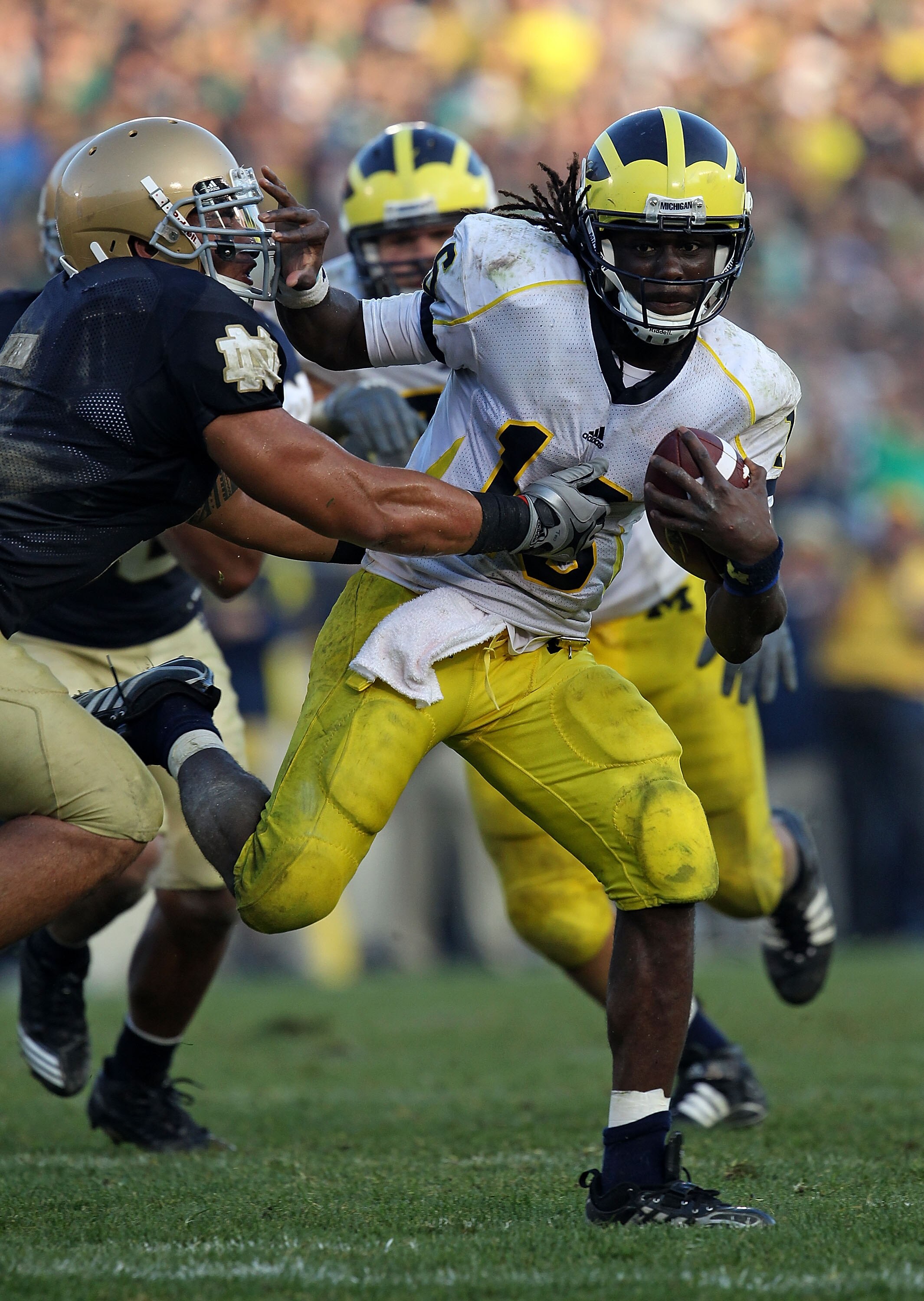 SOUTH BEND, IN - SEPTEMBER 11: Denard Robinson #16 of the Michigan Wolverines pushes off a tackle attempt by Manti Te'o #5 of the Notre Dame Fighting Irish in the final minute at Notre Dame Stadium on September 11, 2010 in South Bend, Indiana. Michigan de