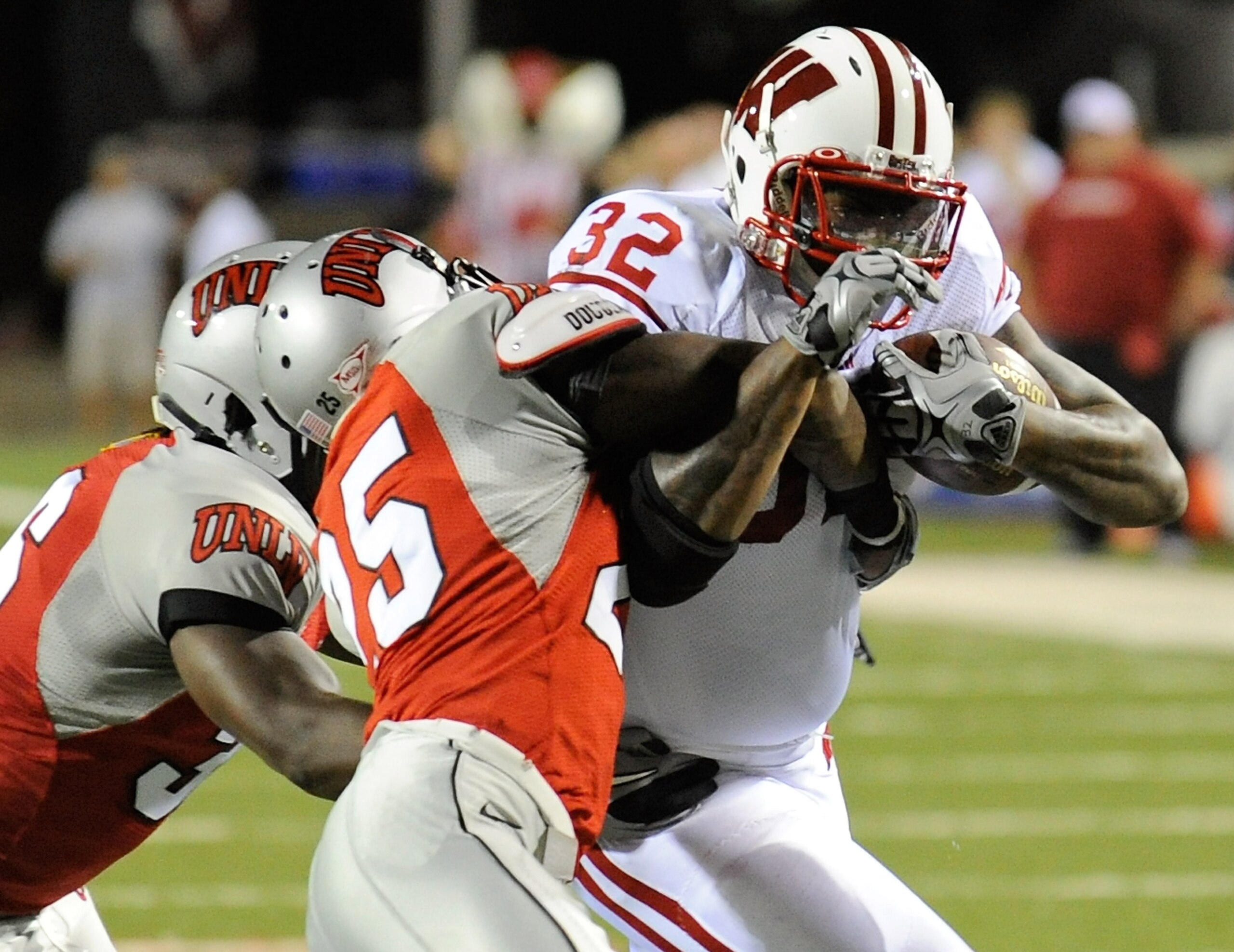 LAS VEGAS - SEPTEMBER 04:  John Clay #32 of the Wisconsin Badgers runs for yardage against Ronnie Paulo #36 and Mike Grant #25 of the UNLV Rebels during the first quarter of their game at Sam Boyd Stadium September 4, 2010 in Las Vegas, Nevada. Wisconsin 