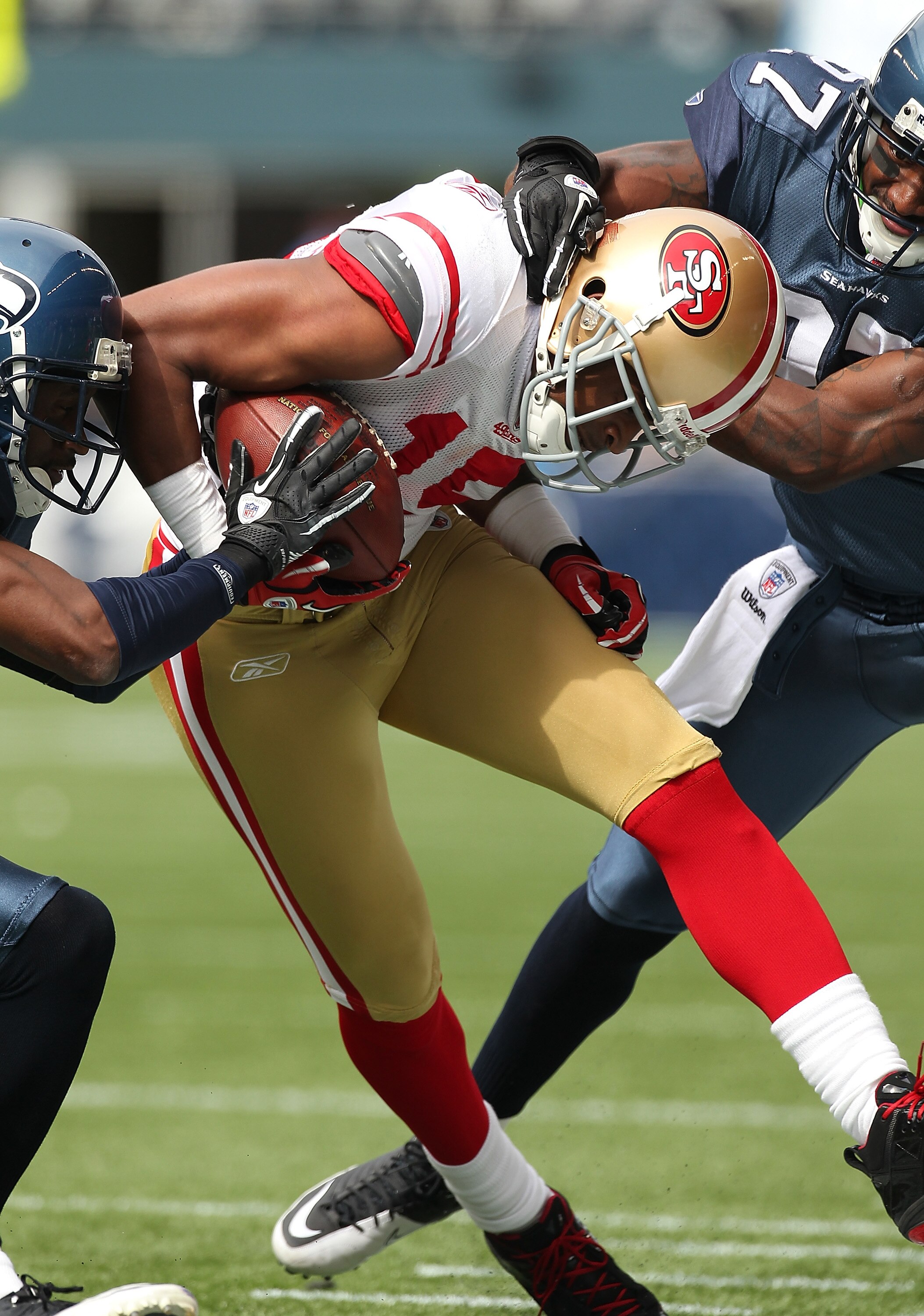 SEATTLE - SEPTEMBER 12:  Wide receiver Michael Crabtree #15 of the San Francisco 49ers is tackled by Jordan Babineaux #27 (R) and Kelly Jennings #21 of the Seattle Seahawks during the NFL season opener at Qwest Field on September 12, 2010 in Seattle, Wash