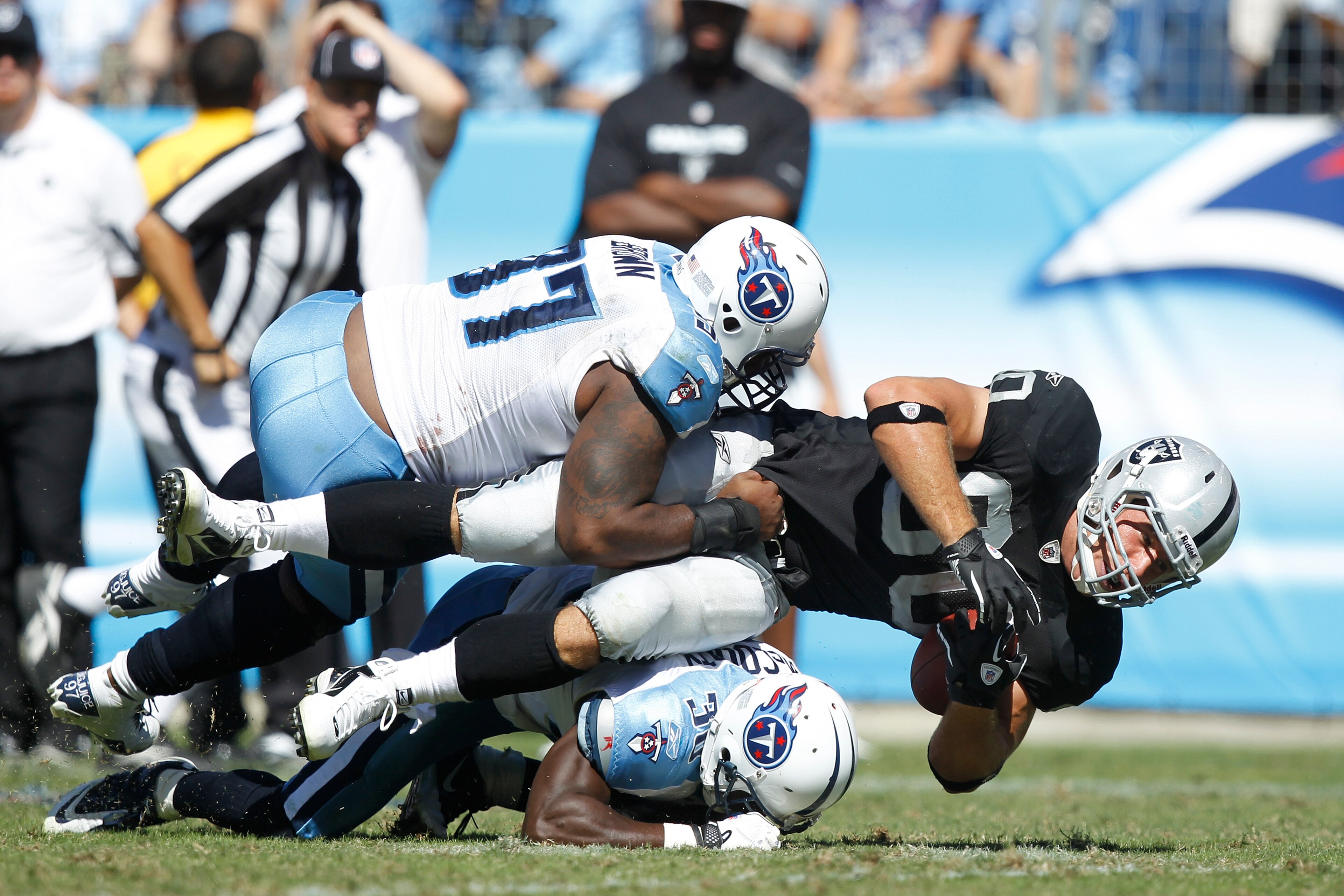 NASHVILLE - SEPTEMBER 12: Tony Brown #97 and Jason McCourty #30 of the Tennessee Titans tackle Zach Miller #80 of the Oakland Raiders during the NFL season opener at LP Field on September 12, 2010 in Nashville, Tennessee. The Titans defeated the Raiders 3