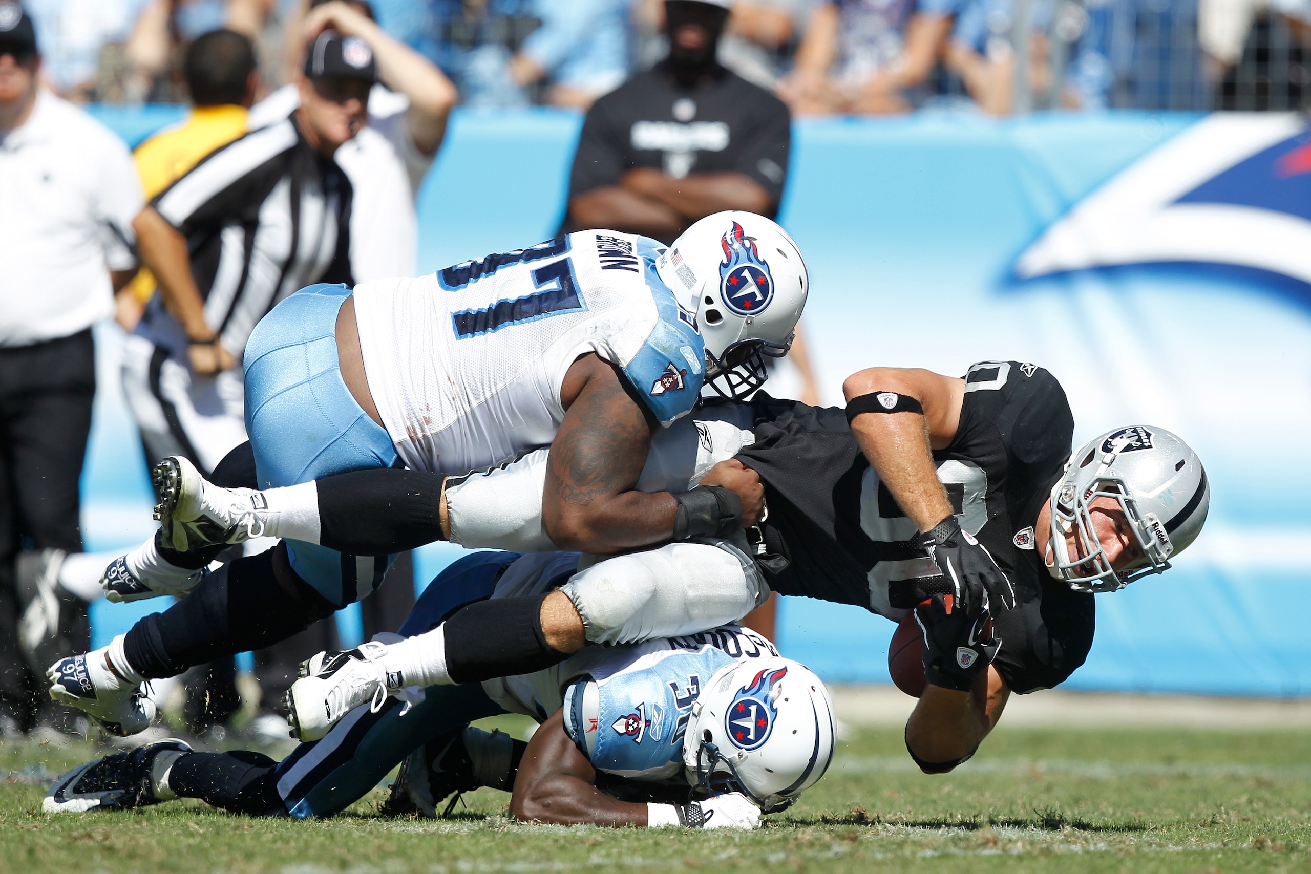 NASHVILLE - SEPTEMBER 12: Tony Brown #97 and Jason McCourty #30 of the Tennessee Titans tackle Zach Miller #80 of the Oakland Raiders during the NFL season opener at LP Field on September 12, 2010 in Nashville, Tennessee. The Titans defeated the Raiders 3 NASHVILLE - SEPTEMBER 12: Tony Brown #97 and Jason McCourty #30 of the Tennessee Titans tackle Zach Miller #80 of the Oakland Raiders during the NFL season opener at LP Field on September 12, 2010 in Nashville, Tennessee. The Titans defeated the Raiders 3
