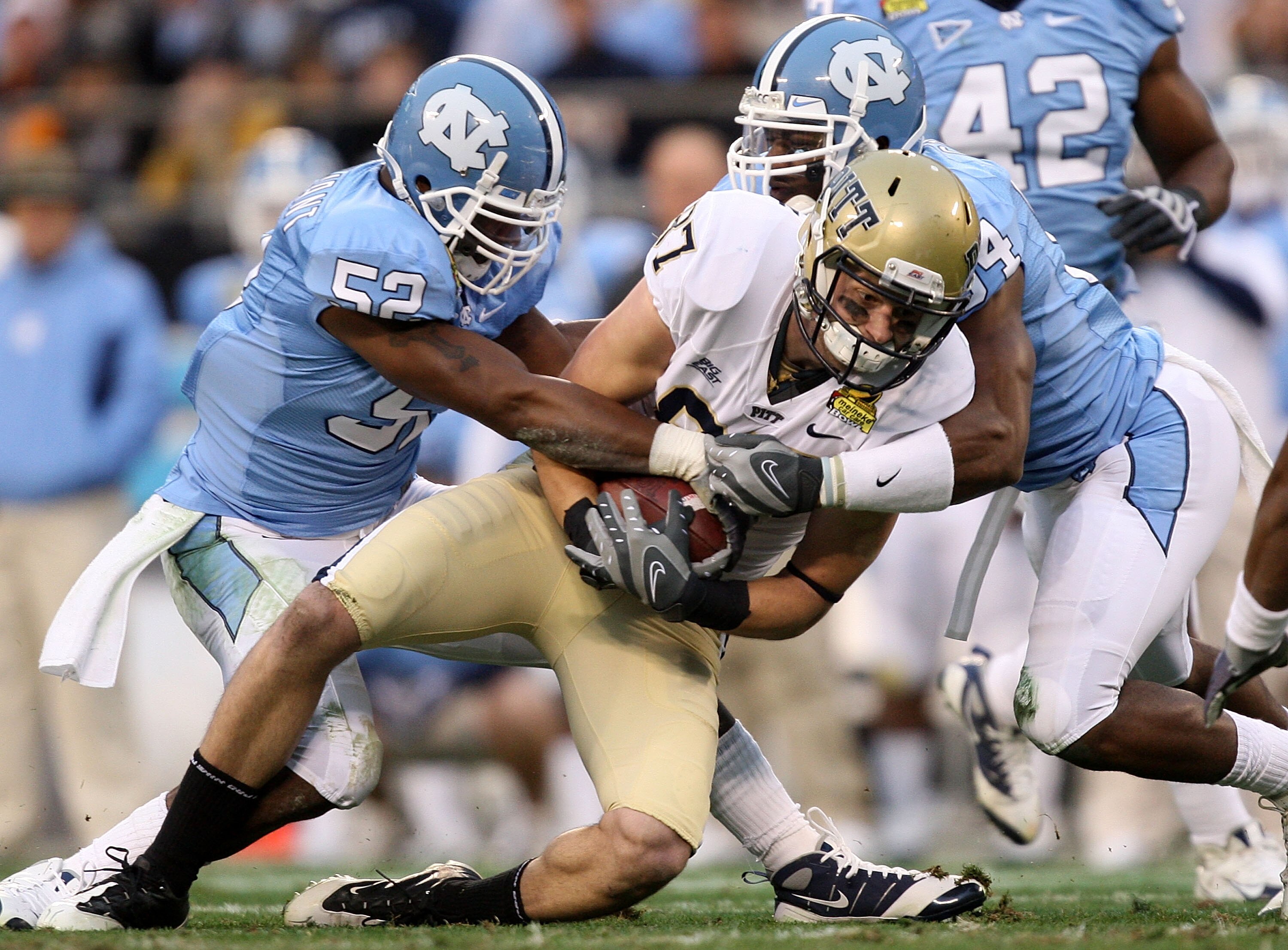 CHARLOTTE, NC - DECEMBER 26:  Mike Shanahan #87 of the Pittsburgh Panthers is tackled by teammates Quan Sturdivant #52 and Bruce Carter #54 of the North Carolina Tar Heels during their game on December 26, 2009 in Charlotte, North Carolina.  (Photo by Str