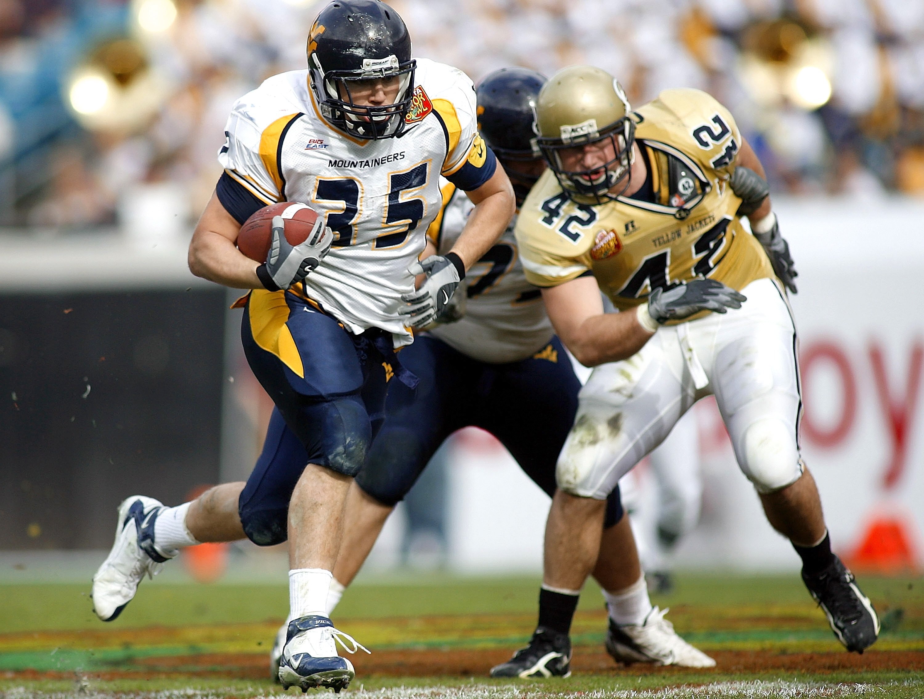 JACKSONVILLE, FL - JANUARY 01:  Full back Owen Schmitt #35 of the West Virginia Mountaineers runs for a touchdown as defensive end Adamm Oliver #42 of the Georgia Tech Yellow Jackets gives chase. (Photo by Marc Serota/Getty Images)