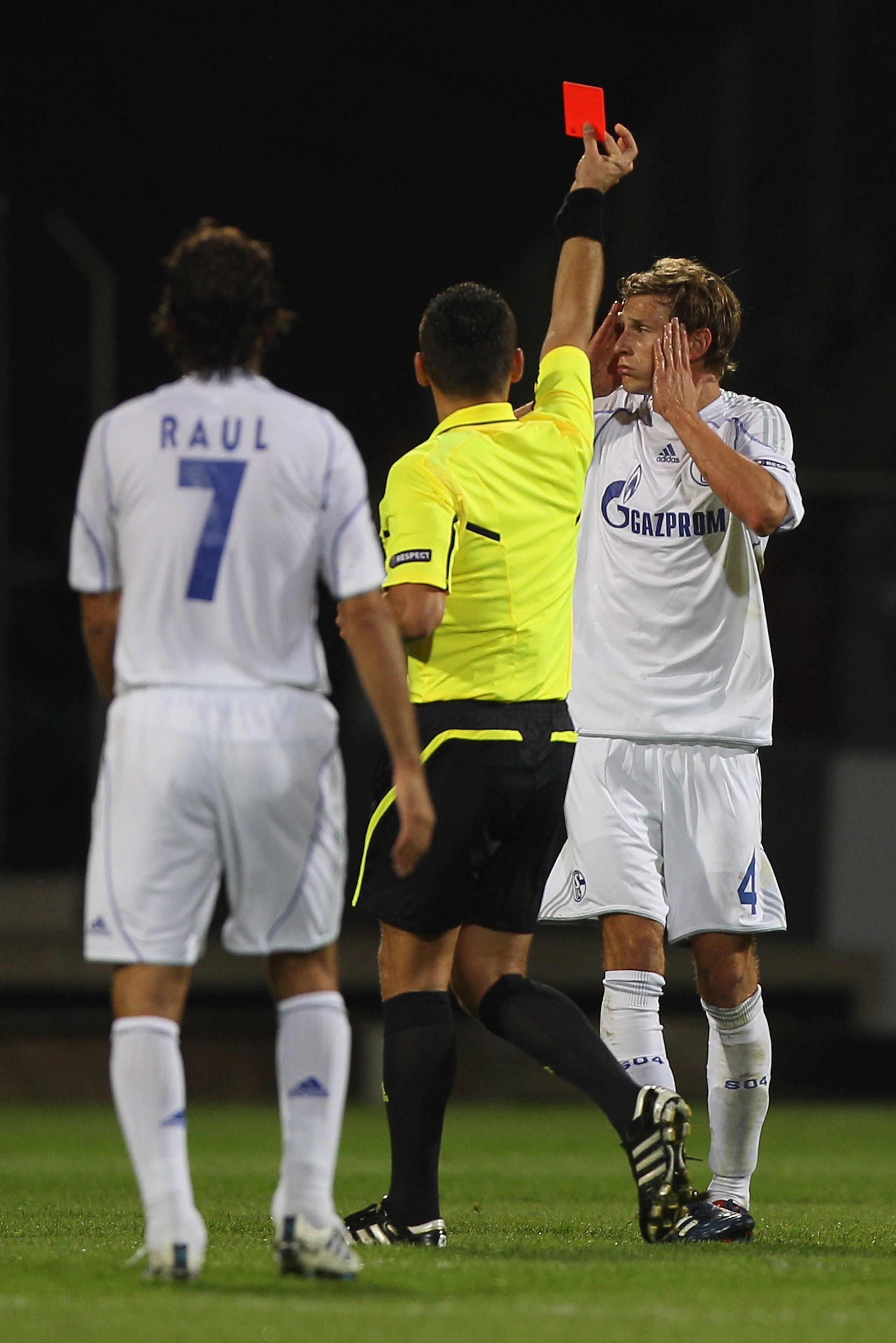 LYON, FRANCE - SEPTEMBER 14:  Benedikt Hoewedes (R) of Schalke is shown a red card by referee Ivan Bebek after a foul on Jimmy Briand during the UEFA Champions League Group B match between Olympique Lyonnais and FC Schalke 04 at the Stade de Gerland on Se