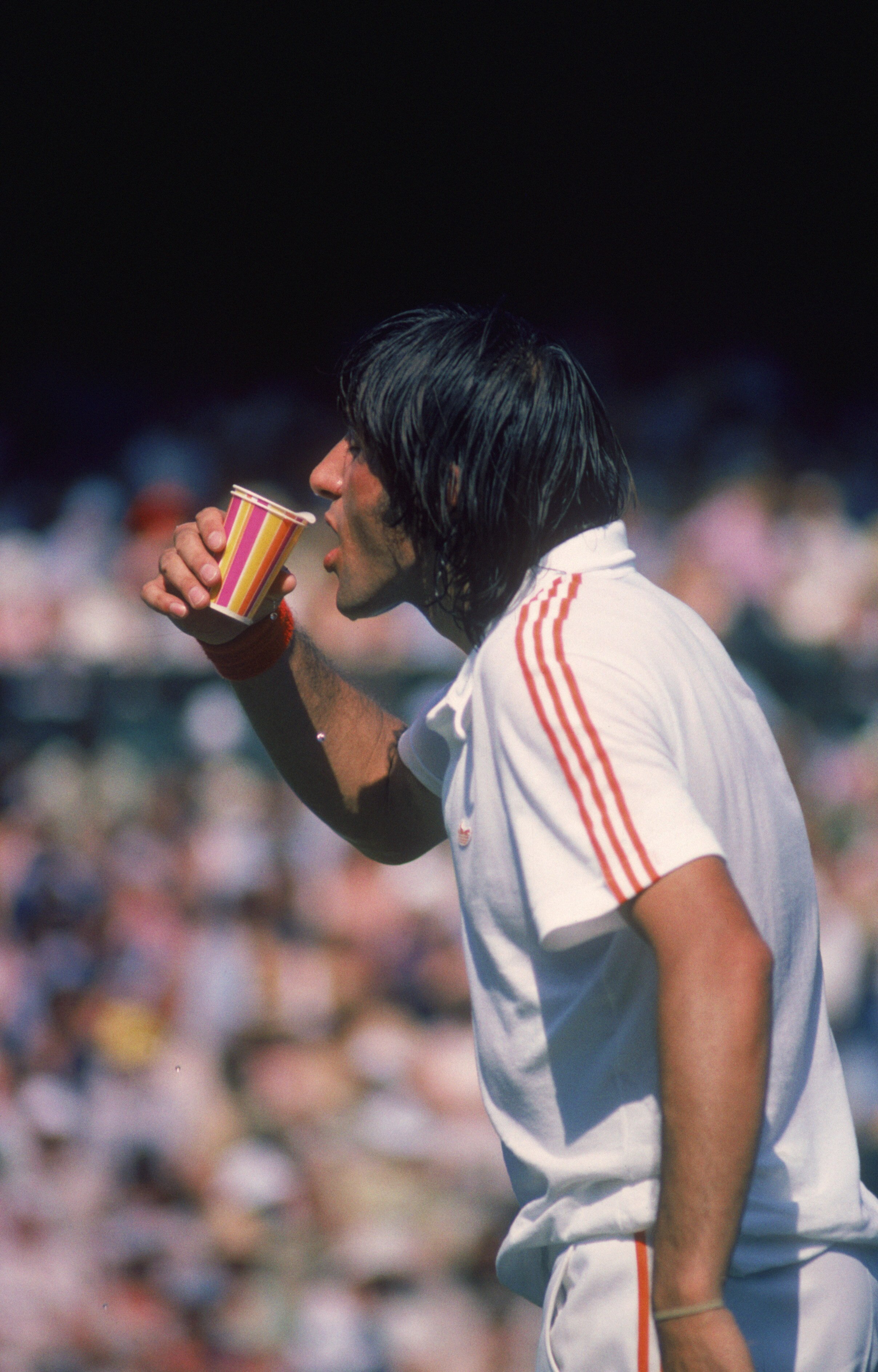 Romanian tennis player Ilie Nastase takes a drink during a match, July 1976. (Photo by Tony Duffy/Getty Images)