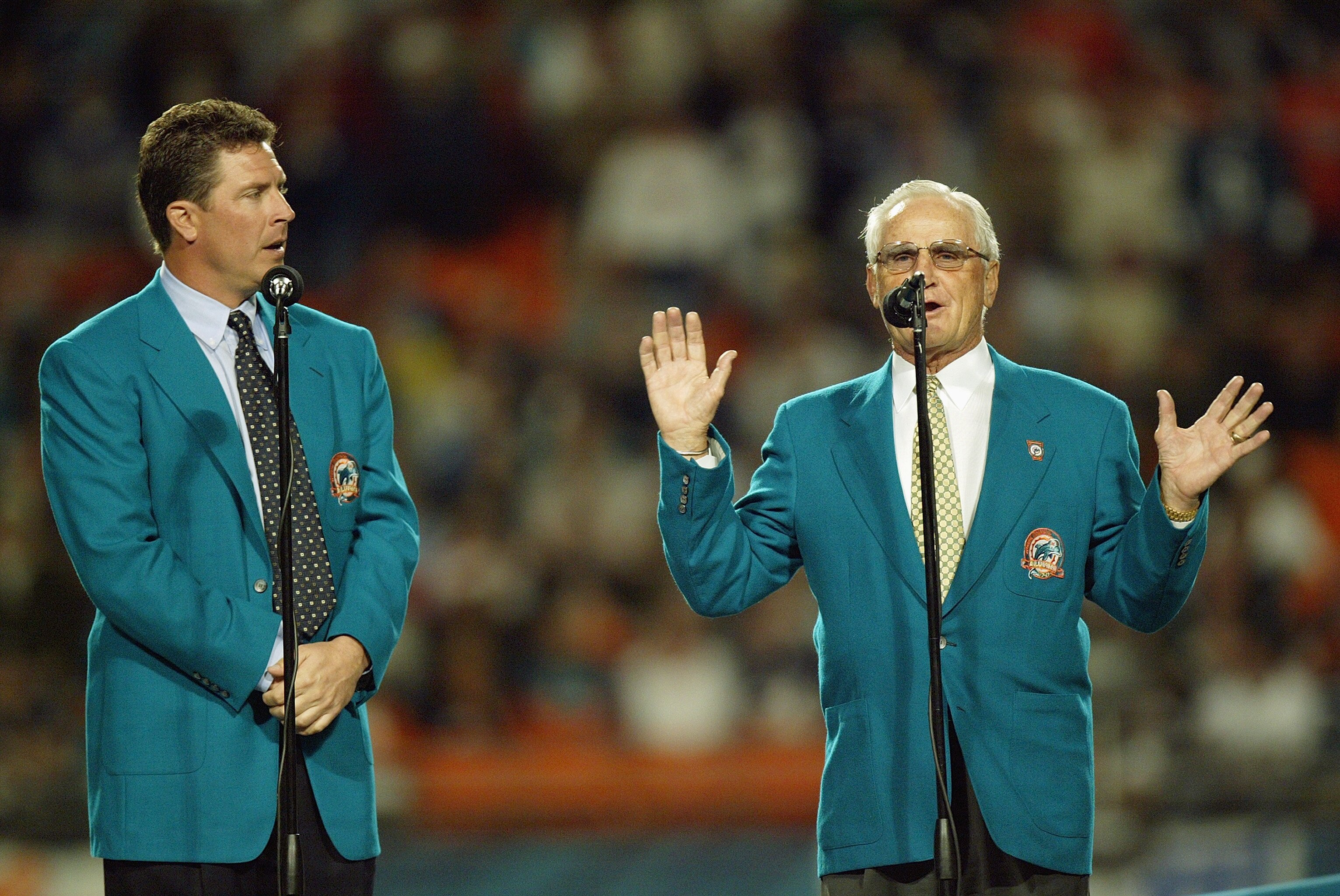 MIAMI - DECEMBER 15:  Former Miami Dolphins coach Don Shula (right) speaks to the crowd as former quarterback Dan Marino watches before inducting former wide receivers Mark Clayton and Mark Duper into the Miami Dolphins Hall of Fame during half time of th