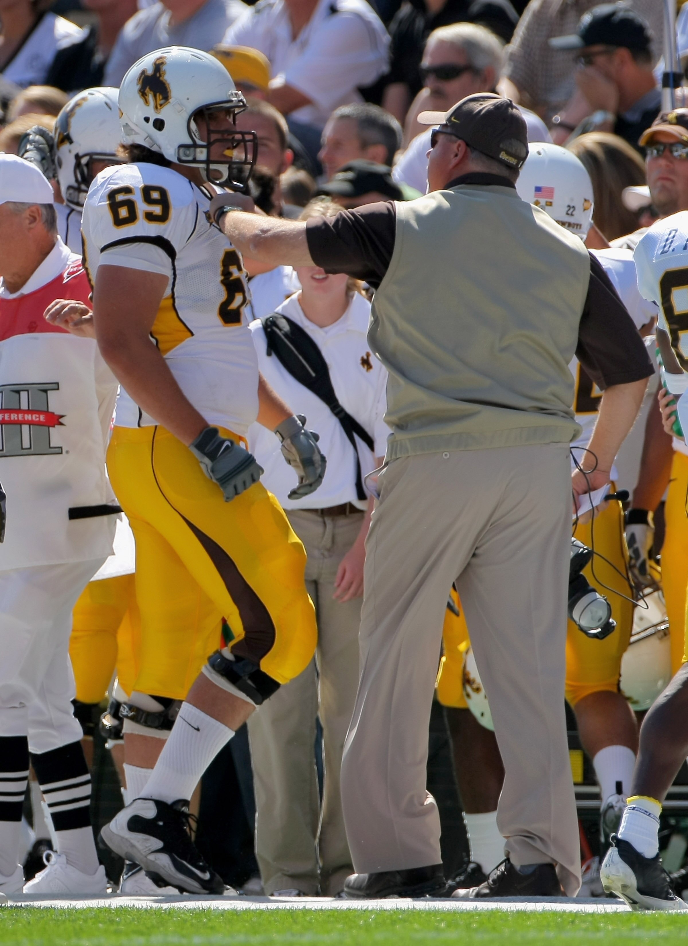 BOULDER, CO - SEPTEMBER 19:  Head coach Dave Christensen of the Wyoming Cowboys grabs right tackle John Hutchins #69 as he comes off the field and has words for him after he was called for illegal motion against the Colorado Buffaloes at Folsom Field on S