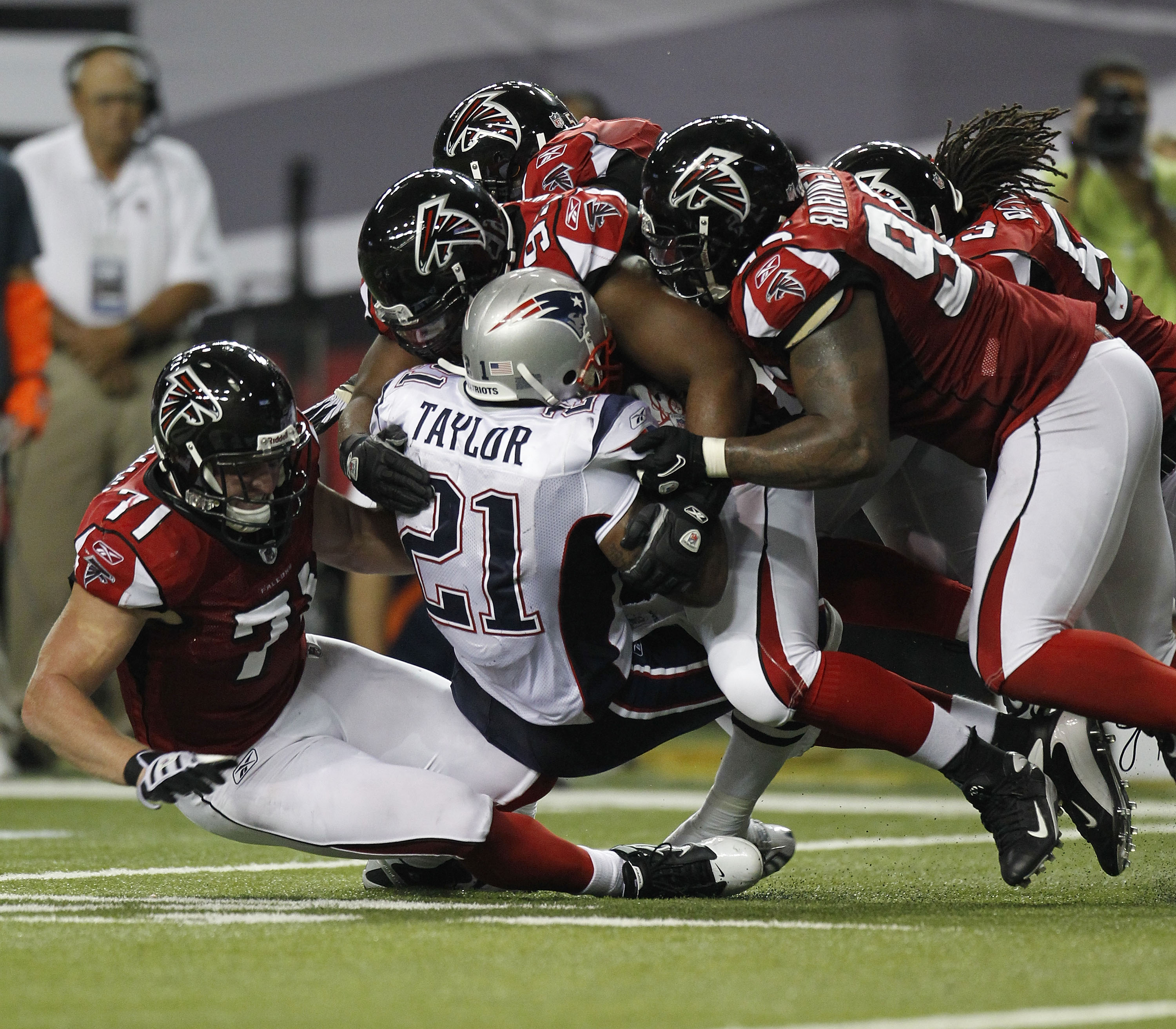 ATLANTA - AUGUST 19:  Running back Fred Taylor #21 of the New England Patriots is tackled by members of the Atlanta Falcons defense during the preseason game at the Georgia Dome on August 19, 2010 in Atlanta, Georgia.  (Photo by Mike Zarrilli/Getty Images