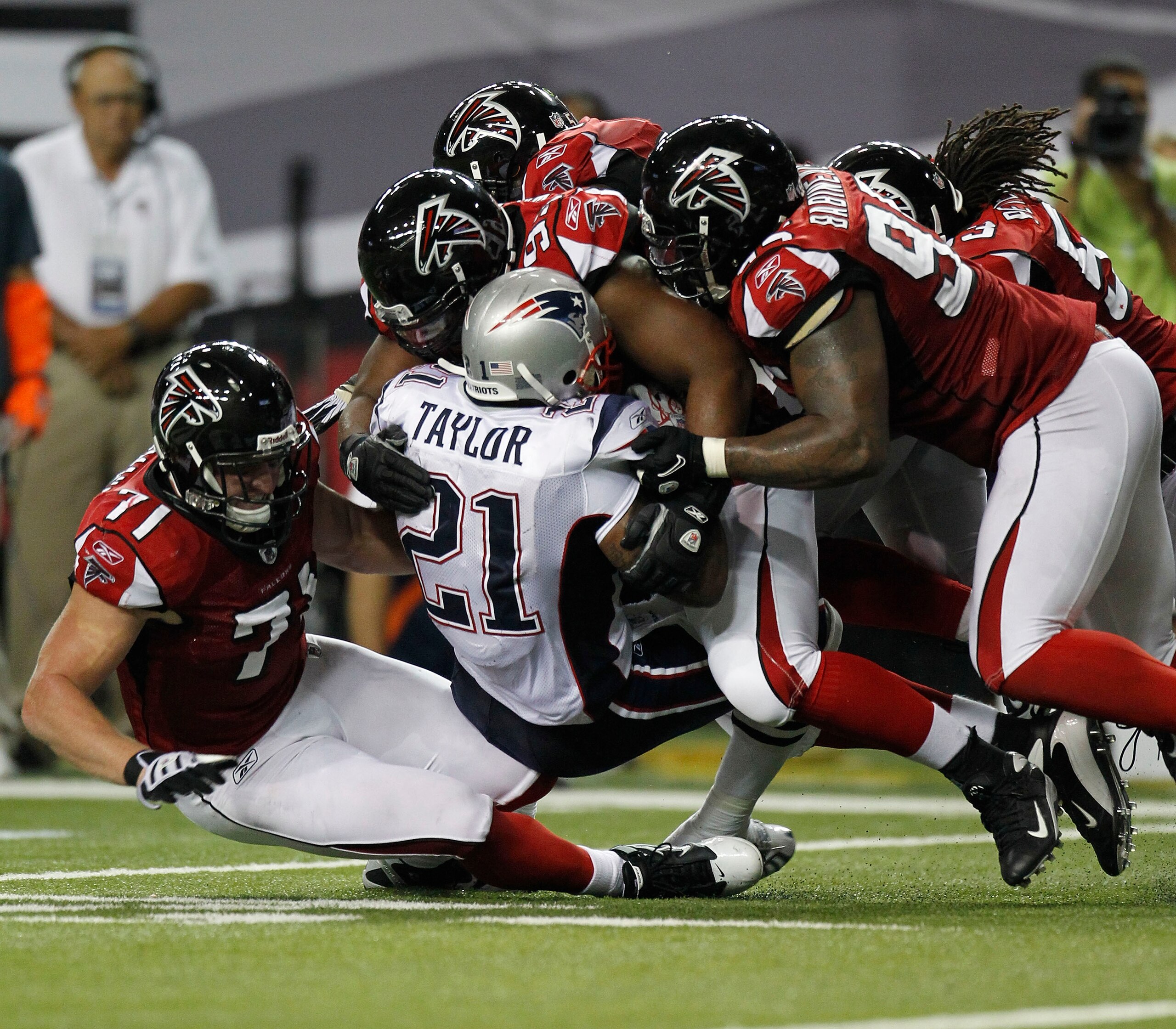 ATLANTA - AUGUST 19:  Running back Fred Taylor #21 of the New England Patriots is tackled by members of the Atlanta Falcons defense during the preseason game at the Georgia Dome on August 19, 2010 in Atlanta, Georgia.  (Photo by Mike Zarrilli/Getty Images
