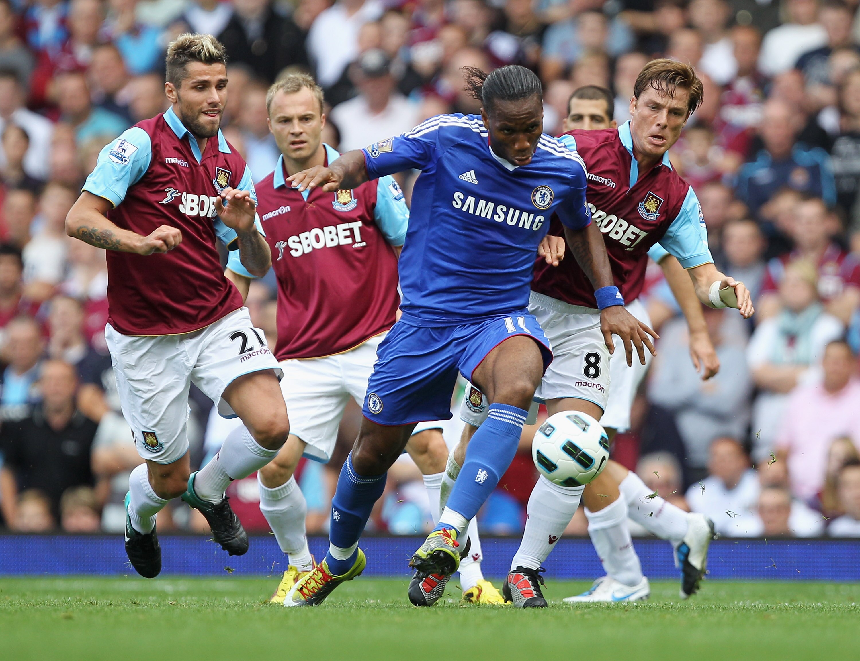 LONDON, ENGLAND - SEPTEMBER 11:  Didier Drogba of Chelsea evades Scott Parker (8) and Valon Behrami of West Ham United (L) during the Barclays Premier League match between West Ham United and Chelsea at the Boleyn Ground on September 11, 2010 in London, E