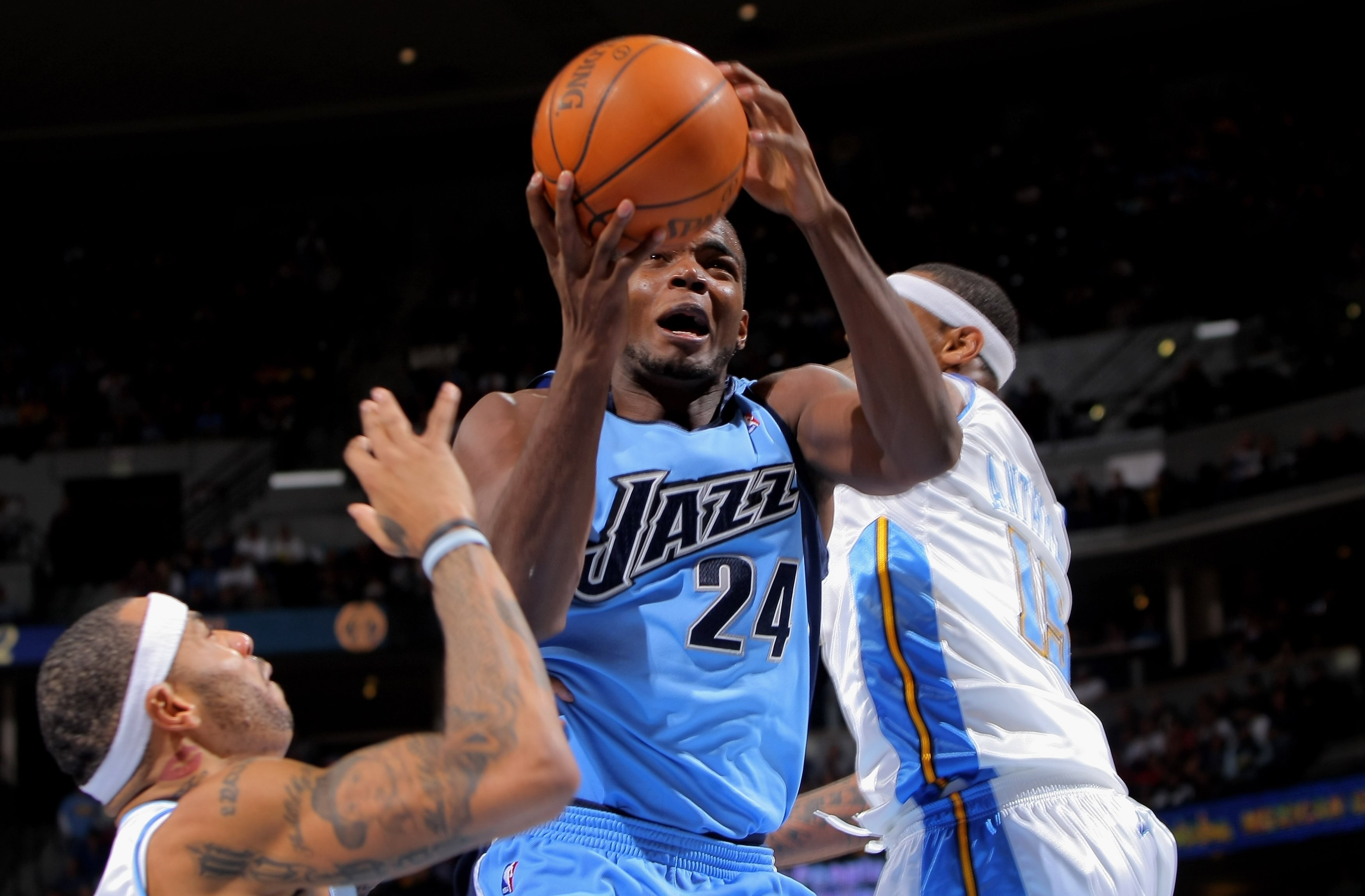 DENVER - OCTOBER 28:  Paul Milsap #24 of the Utah Jazz heads takes a shot between Kenyon Martin #4 and Carmelo Anthony #24 of the Denver Nuggets during NBA action at Pepsi Center on October 28, 2009 in Denver, Colorado. The Nuggets defeated the Jazz 114-1