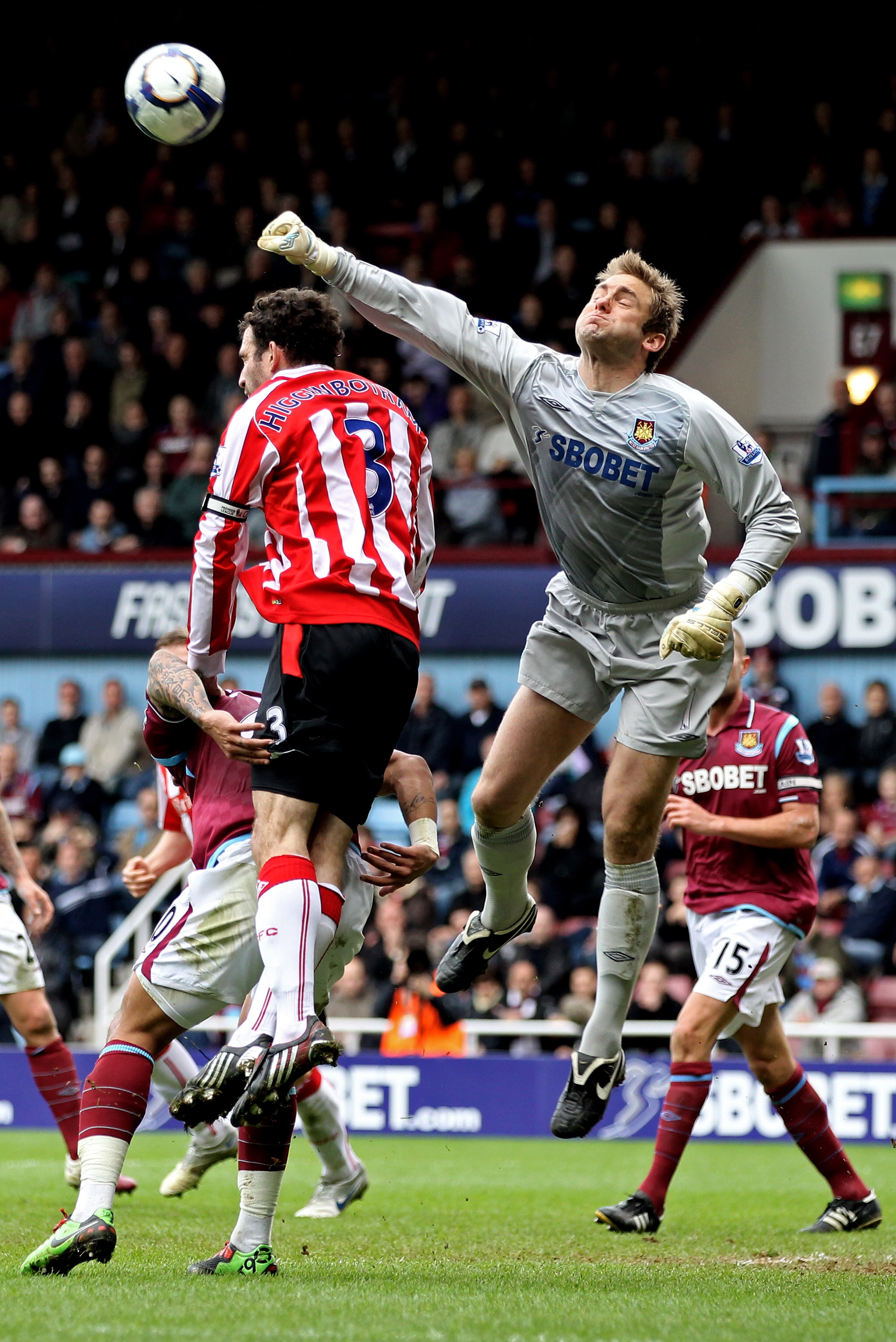 LONDON, ENGLAND - MARCH 27:  Goalkeeper Robert Green of West Ham punches the ball clear as Danny Higginbotham of Stoke closes in during the Barclays Premier League match between West Ham United and Stoke City at the Boleyn Ground on March 27, 2010 in Lond