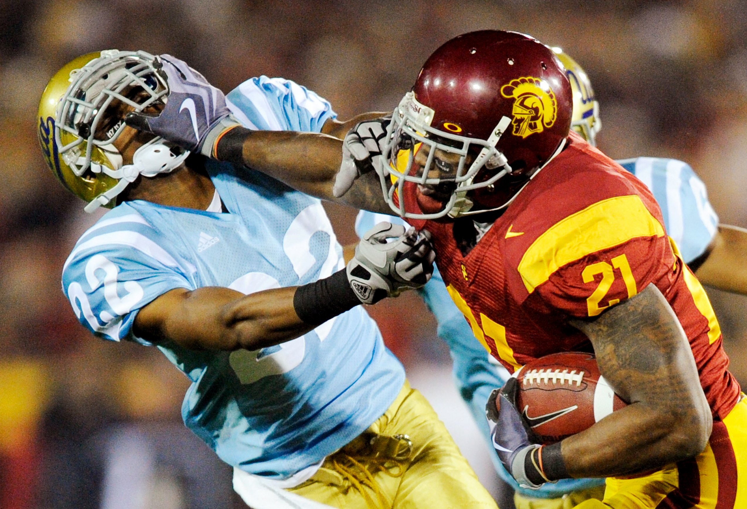 LOS ANGELES, CA - NOVEMBER 28:  Tailback Allen Bradford #21 of the USC Trojans stiff arms defensive back Sheldon Price #22 of the UCLA Bruins as he runs for a gain during the second quarter of the NCAA college football game at Los Angeles Memorial Coliseu