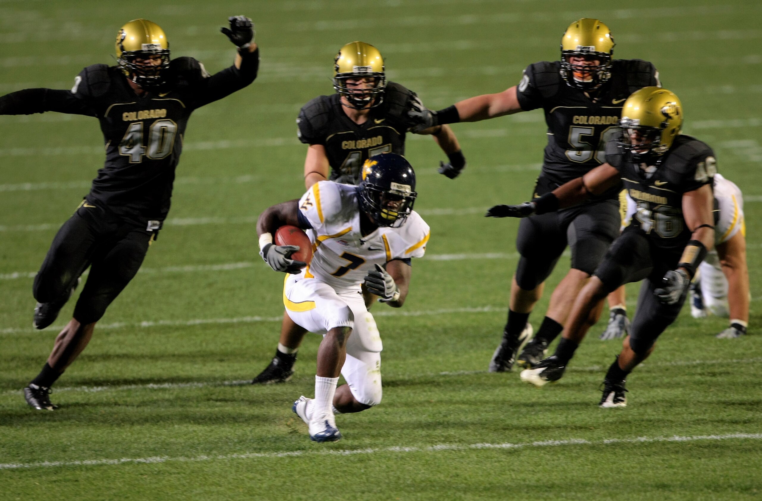 BOULDER, CO - SEPTEMBER 18: Running back Noel Devine #7 of the West Virginia Mountaineers tries to elude the Colorado Buffaloes defense at Folsom Field September 18, 2008 in Boulder, Colorado. Colorado defeated West Virginia 17-14 in overtime. (Photo by BOULDER, CO - SEPTEMBER 18: Running back Noel Devine #7 of the West Virginia Mountaineers tries to elude the Colorado Buffaloes defense at Folsom Field September 18, 2008 in Boulder, Colorado. Colorado defeated West Virginia 17-14 in overtime. (Photo by