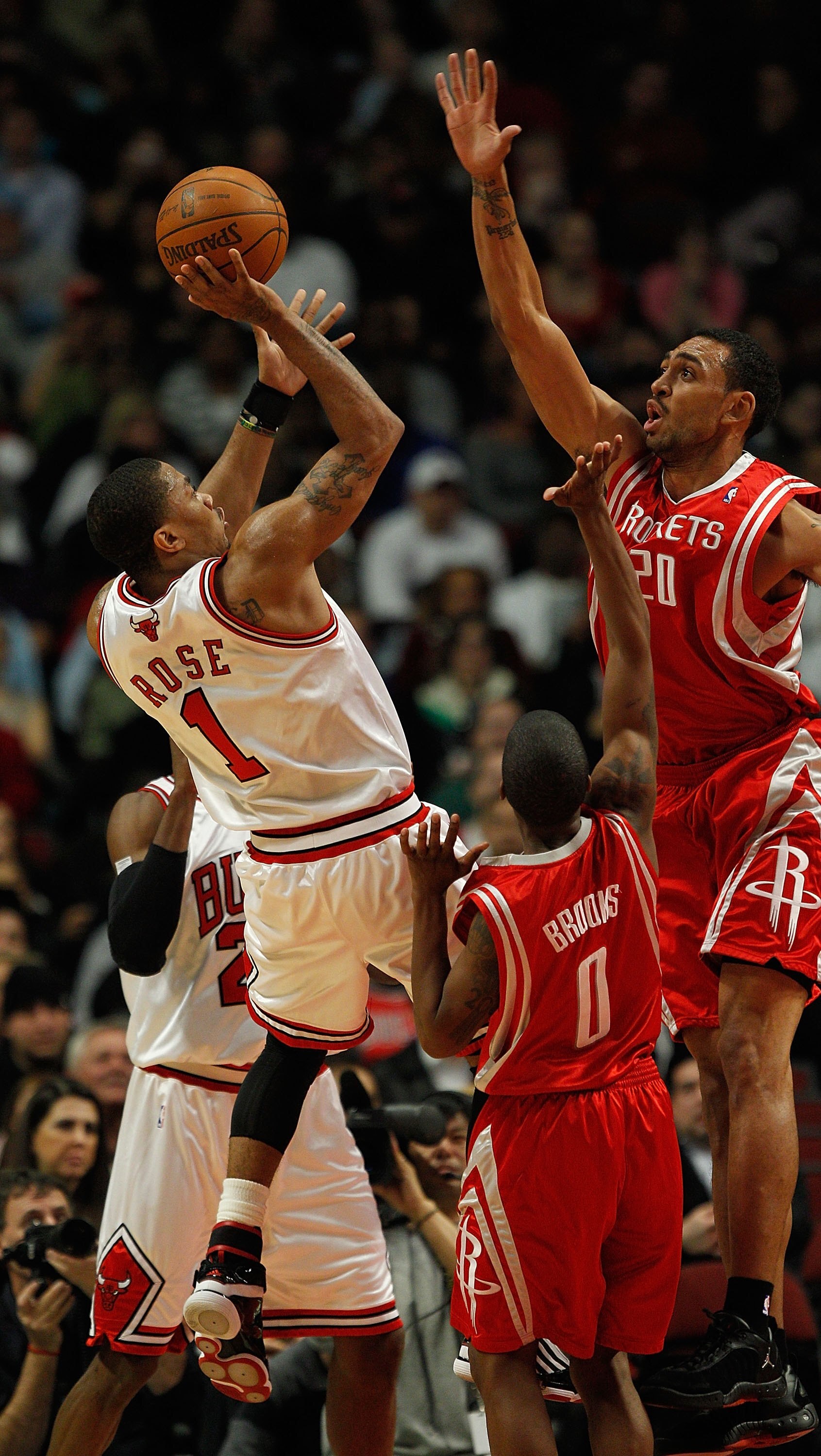CHICAGO - MARCH 22: Derrick Rose #1 of the Chicago Bulls puts up a shot against Aaron Brooks #0 and Jared Jefferies #20 of the Houston Rockets at the United Center on March 22, 2010 in Chicago, Illinois. NOTE TO USER: User expressly acknowledges and agree