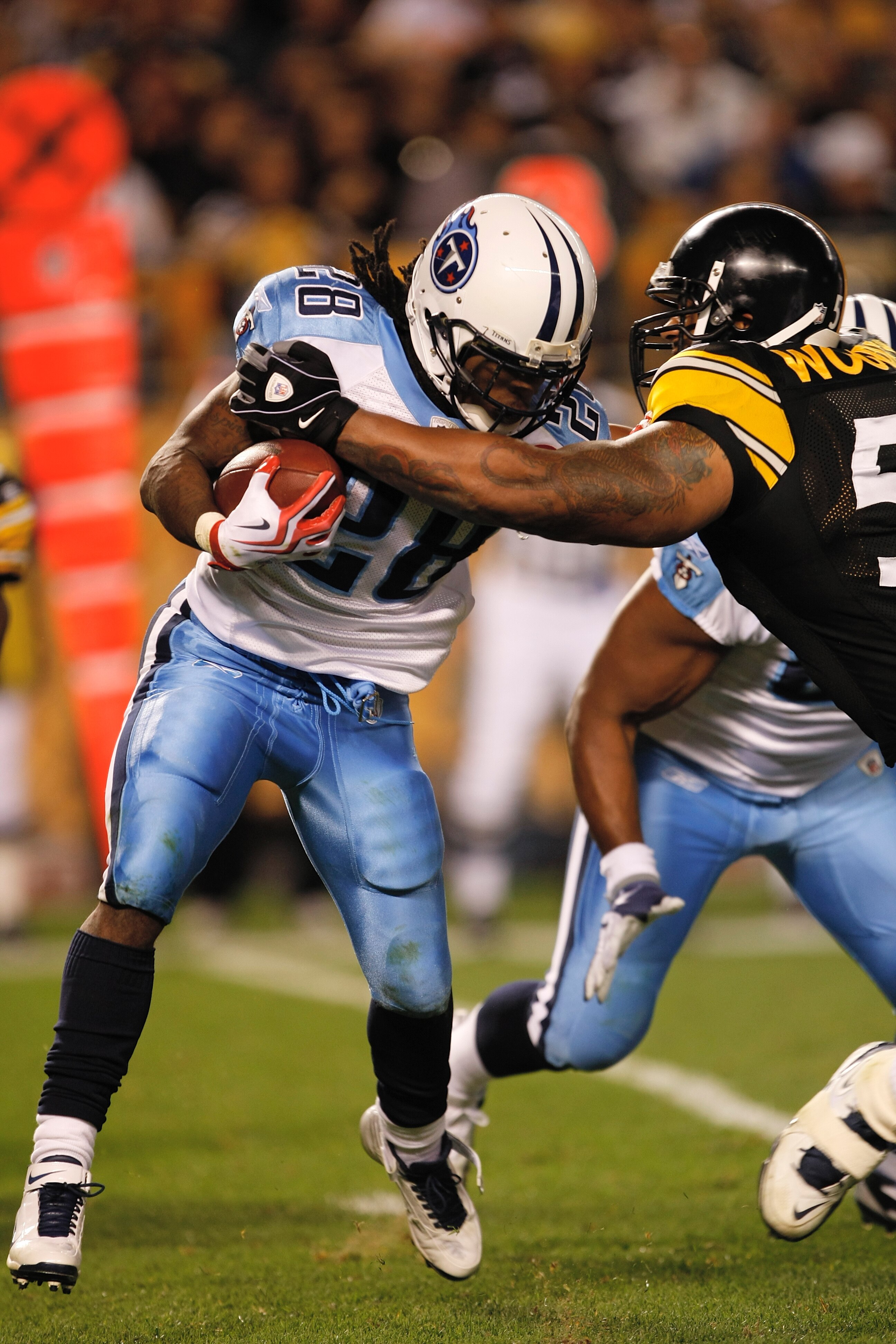 PITTSBURGH, PA - SEPTEMBER 10: Running back Chris Johnson #28 of the Tennessee Titans runs with the football as he is grabbed by LaMarr Woodley #56 of the Pittsburgh Steelers at Heinz Field on September 10, 2009 in Pittsburgh, Pennsylvania. The Steelers d