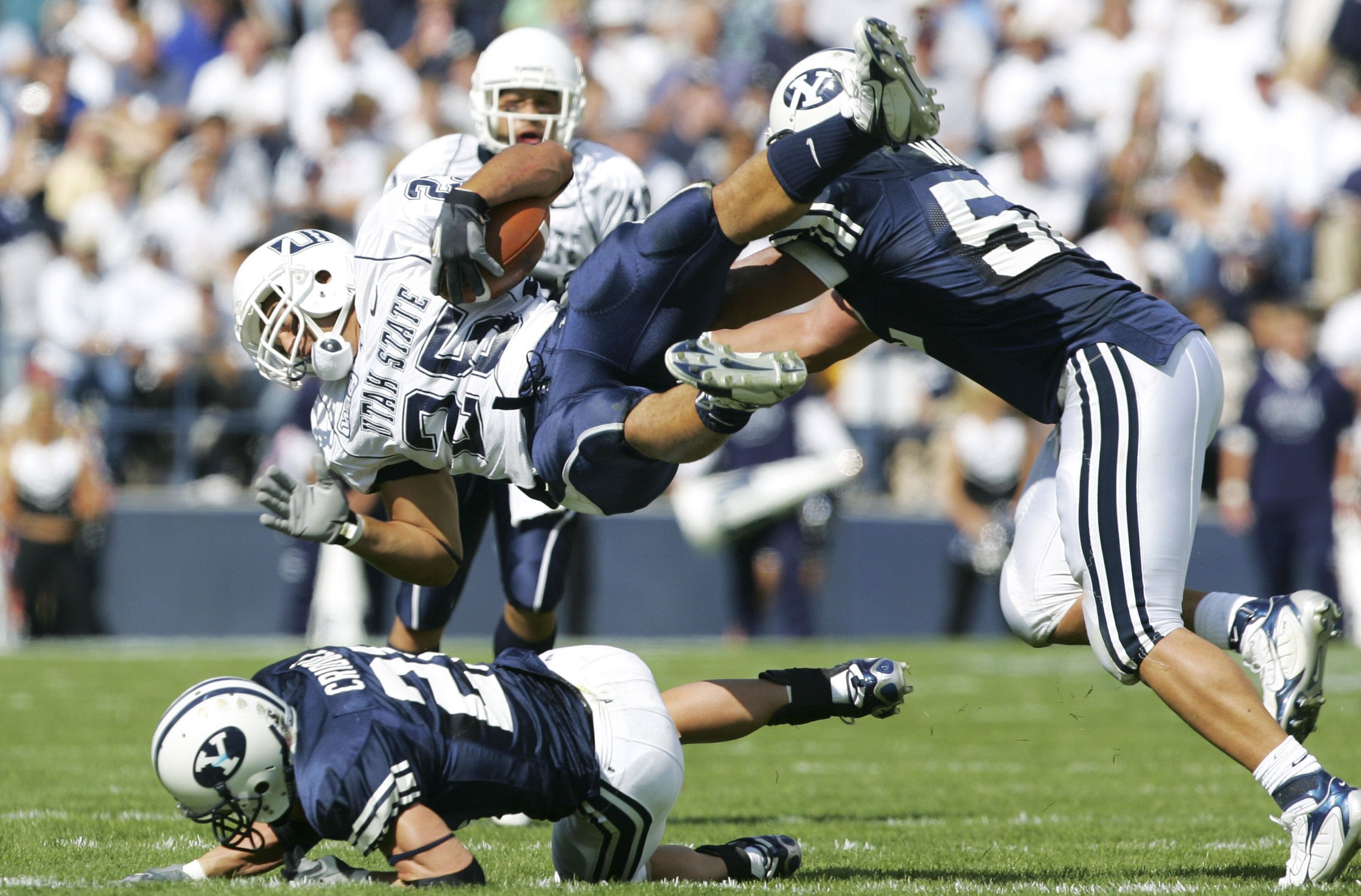 PROVO, UT - SEPTEMBER 23:   Lynwood Johnson #25 of Utah State is tackled by Ben Criddle #25 and Aaron Wagner #52 of BYU September 23, 2006 in Provo, Utah. BYU defeated Utah State 38-0.  (Photo by Kent Horner/Getty Images)