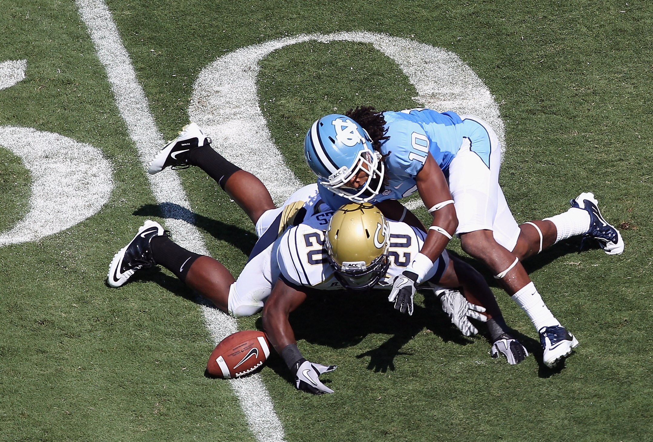 CHAPEL HILL, NC - SEPTEMBER 18:  Roddy Jones #20 of the Georgia Tech Yellow Jackets dives for a loose ball with Tre Boston #10 of the North Carolina Tar Heels during their game at Kenan Stadium on September 18, 2010 in Chapel Hill, North Carolina.  (Photo