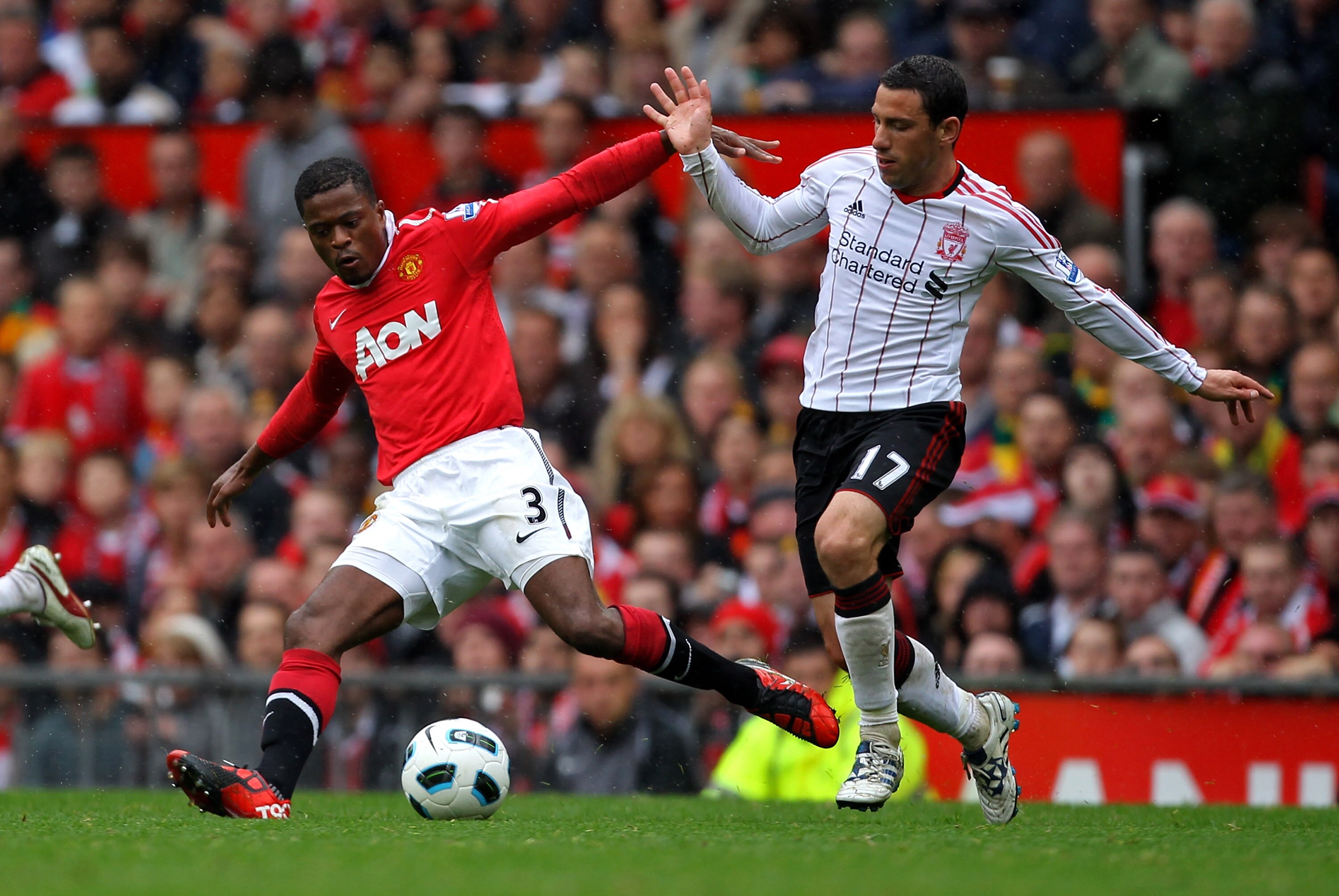 MANCHESTER, ENGLAND - SEPTEMBER 19: Patrice Evra of Manchester United tussles for posession with Maxi Rodriguez of Liverpool during the Barclays Premier League match between Manchester United and Liverpool at Old Trafford on September 19, 2010 in Manches MANCHESTER, ENGLAND - SEPTEMBER 19: Patrice Evra of Manchester United tussles for posession with Maxi Rodriguez of Liverpool during the Barclays Premier League match between Manchester United and Liverpool at Old Trafford on September 19, 2010 in Manches