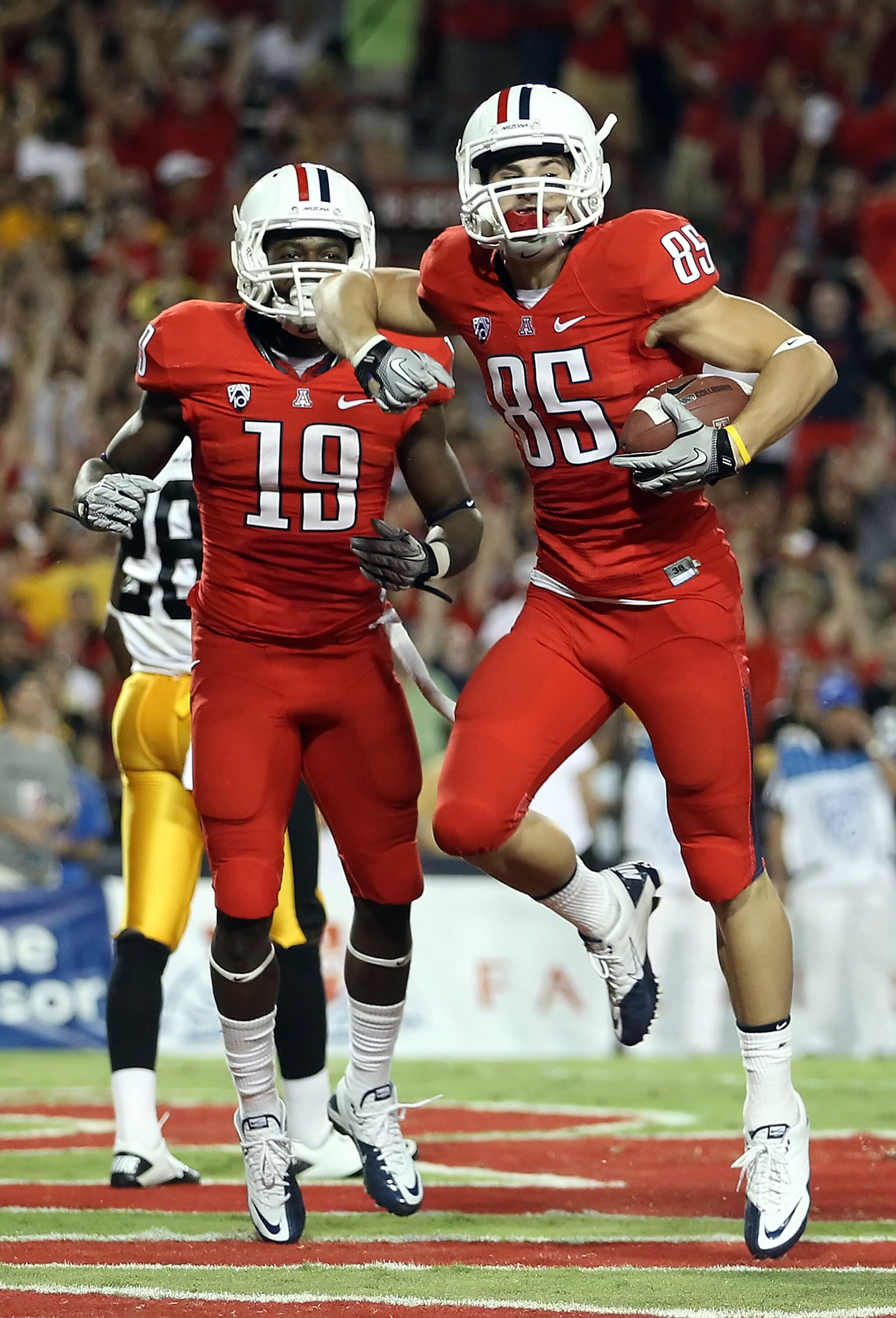 TUCSON, AZ - SEPTEMBER 18:  Wide receiver David Douglas #85 of the Arizona Wildcats celebrates with William Wright #19 after Douglas scored on a 5 yard touchdown reception against the Iowa Hawkeyes during the first quarter of the college football game at