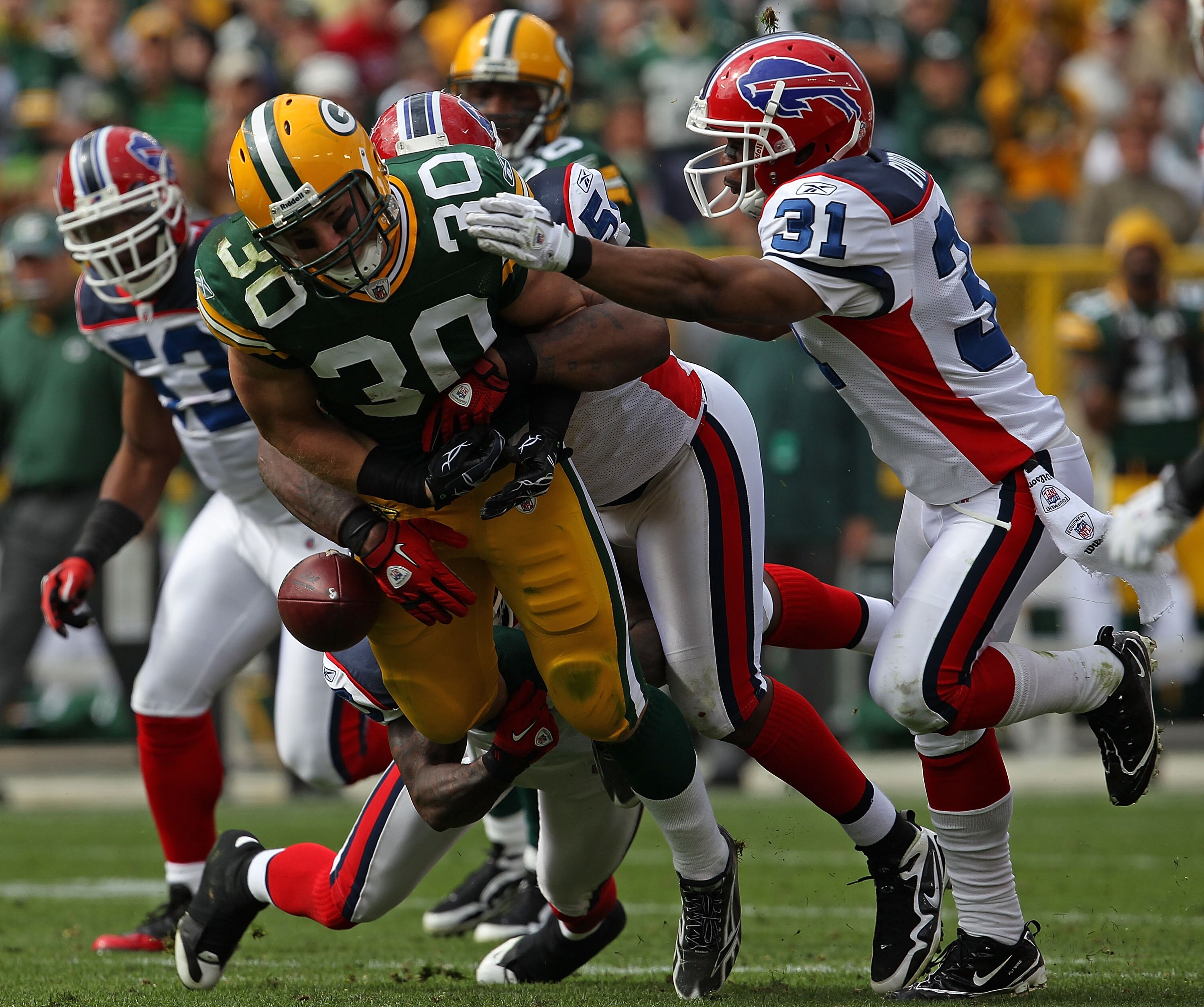 GREEN BAY, WI - SEPTEMBER 19: John Kuhn #30 of the Green Bay Packers fumbles the ball as he is hit by members of the Buffalo Bills defense including Jarius Byrd #31 at Lambeau Field on September 19, 2010 in Green Bay, Wisconsin. The Packers defeated the B