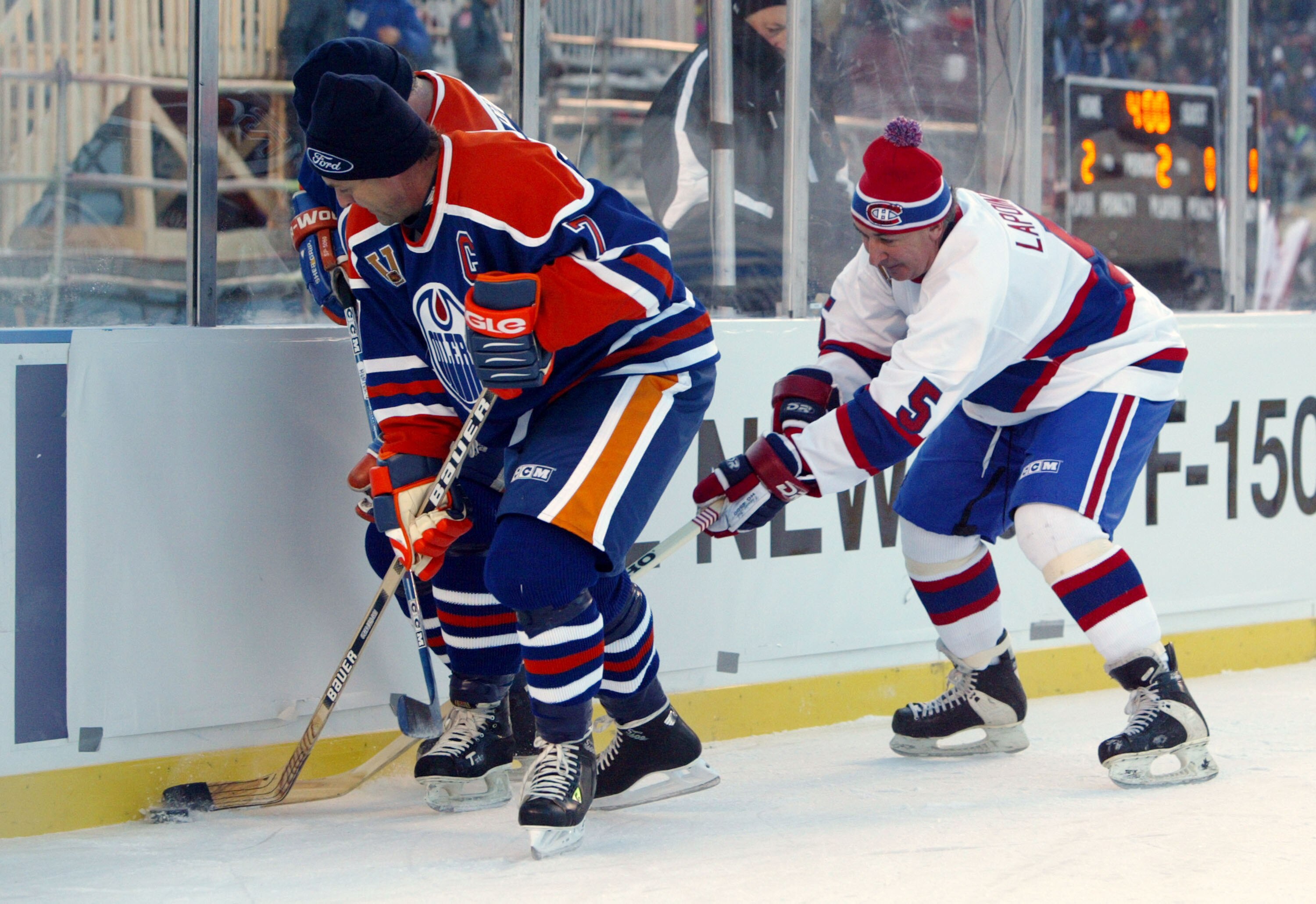 EDMONTON, CANADA - NOVEMBER 22:  Ron Chipperfield #7 of the Edmonton Oilers tries to skate away with the puck as Guy Lapointe #5 of the Montreal Canadiens reaches in  with his stick during the Molson Canadien Heritage Classic Megastars Game on November 22