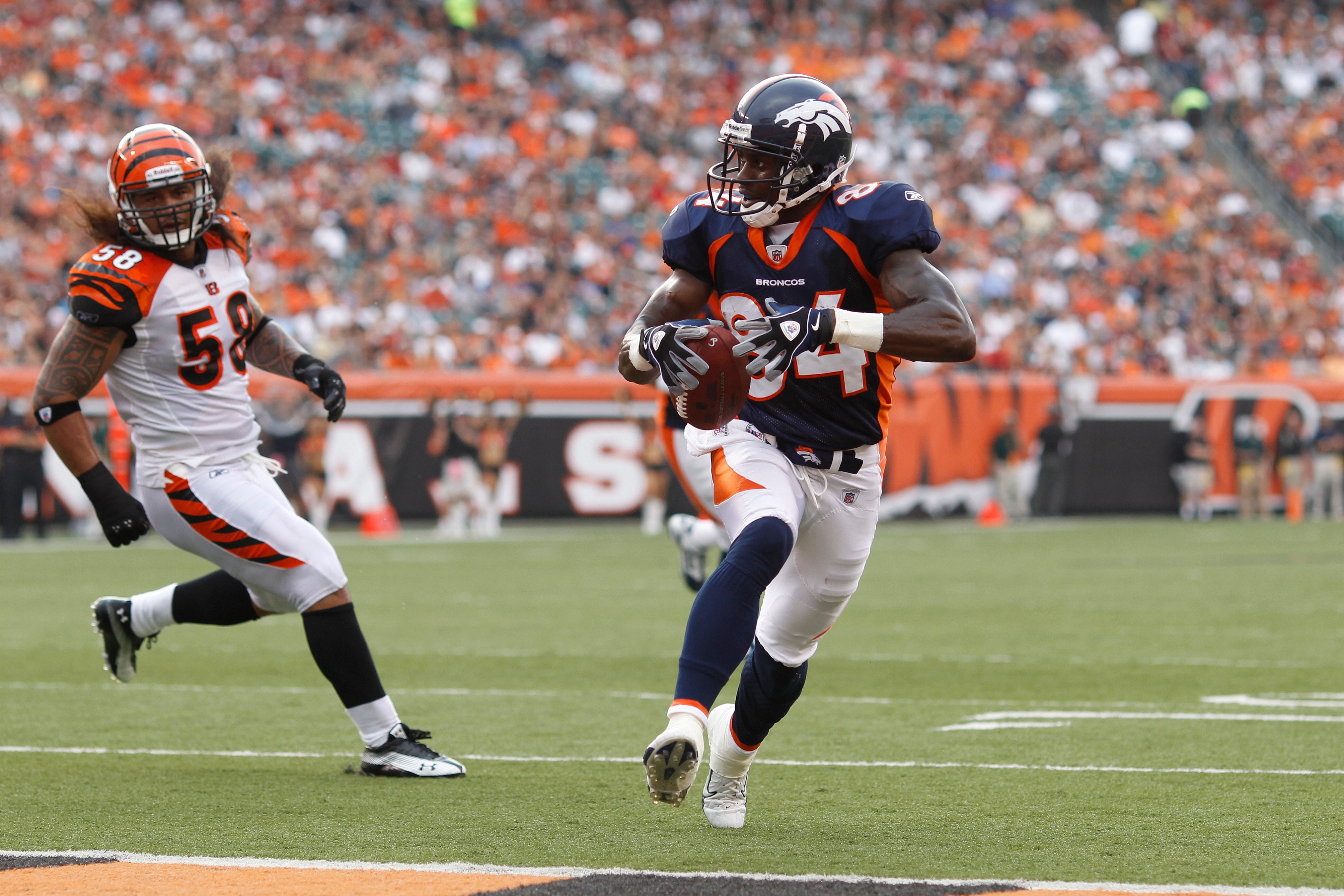 CINCINNATI, OH - AUGUST 15: Brandon Lloyd #84 of the Denver Broncos runs into the end zone for a touchdown ahead of Rey Maualuga #58 of the Cincinnati Bengals during a preseason game at Paul Brown Stadium on August 15, 2010 in Cincinnati, Ohio. (Photo by