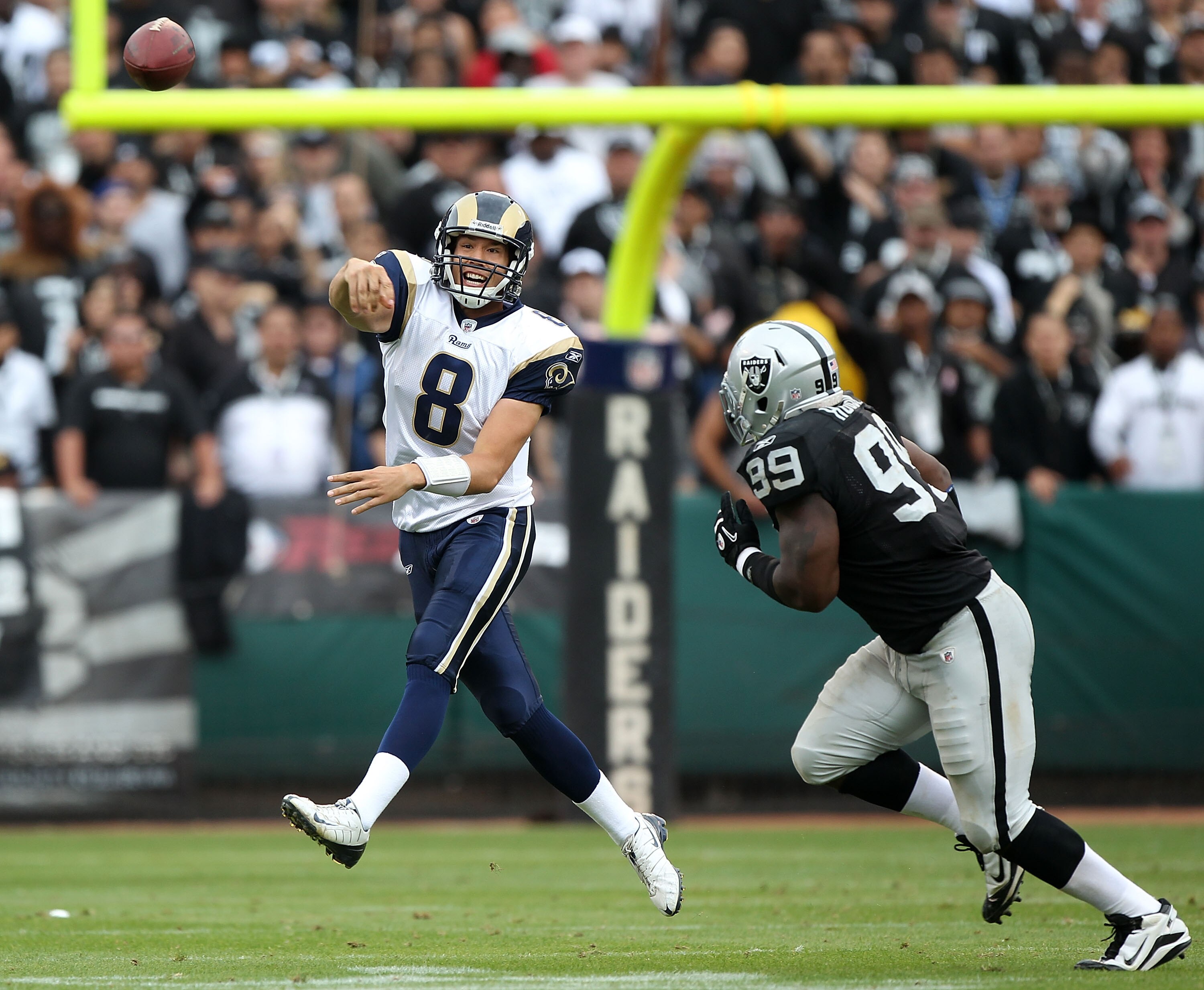 OAKLAND, CA - SEPTEMBER 19:  Sam Bradford #8 of the St. Louis Rams is pressured by Lamarr Houston #99 of the Oakland Raiders during an NFL game at Oakland-Alameda County Coliseum on September 19, 2010 in Oakland, California.  (Photo by Jed Jacobsohn/Getty