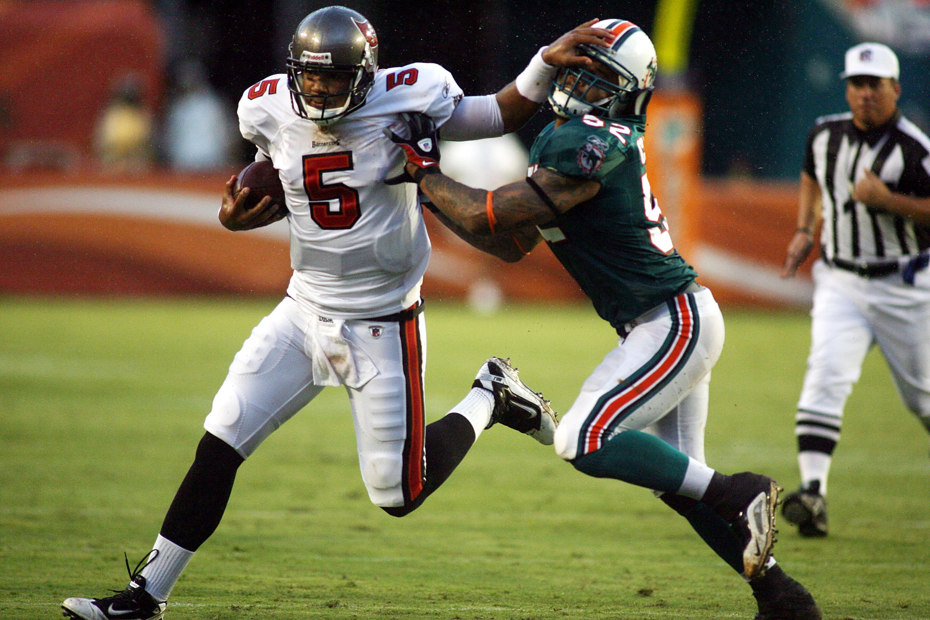 MIAMI - AUGUST 14:  Linebacker Channing Crowder #52 of the Miami Dolphins (R) tackles Quarterback Josh Freemen #5 of the Tampa Bay Buccaneers during the preseason game at Sun Life Stadium on August 14, 2010 in Miami, Florida.  (Photo by Marc Serota/Getty