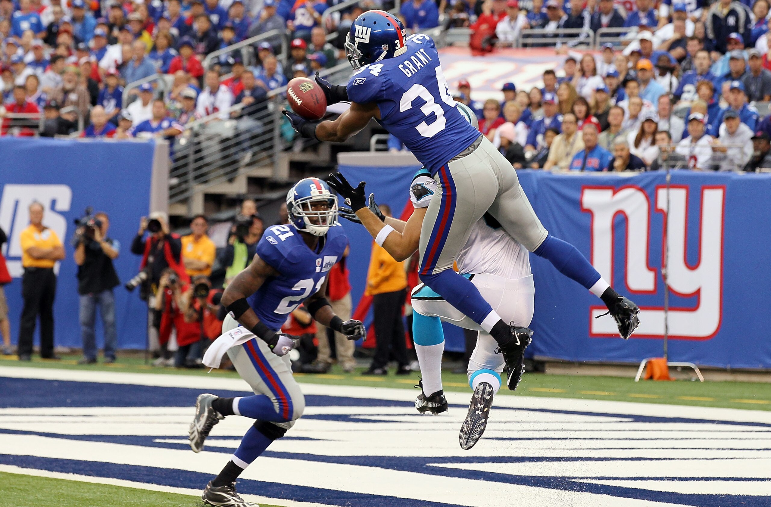 EAST RUTHERFORD, NJ - SEPTEMBER 12:  Deon Grant #34 of the New York Giants intercepts a pass in the endzone intended for Gary Barnidge #82 of the Carolina Panthers as teammate Kenny Phillips #21 defends during the first quarter on September 12, 2010 at th