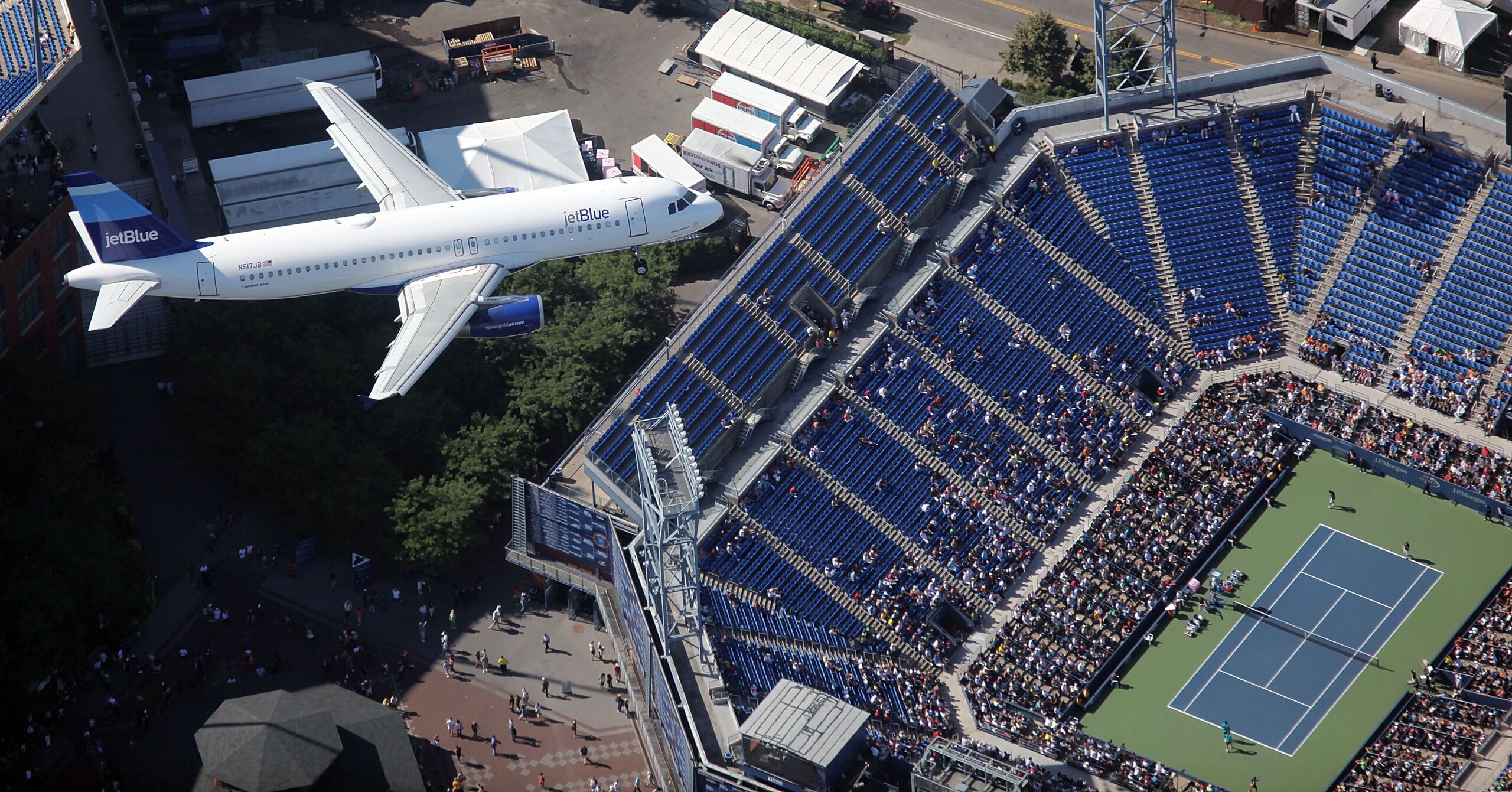NEW YORK - SEPTEMBER 13: A JetBlue airplane files over as Lukas Dlouhy of the Czech Republic (L) and Leander Paes of India play against Mahesh Bhupathi of India and Mark Knowles of the Bahamas during the men's doubles final on day fourteen of the 2009 U.S