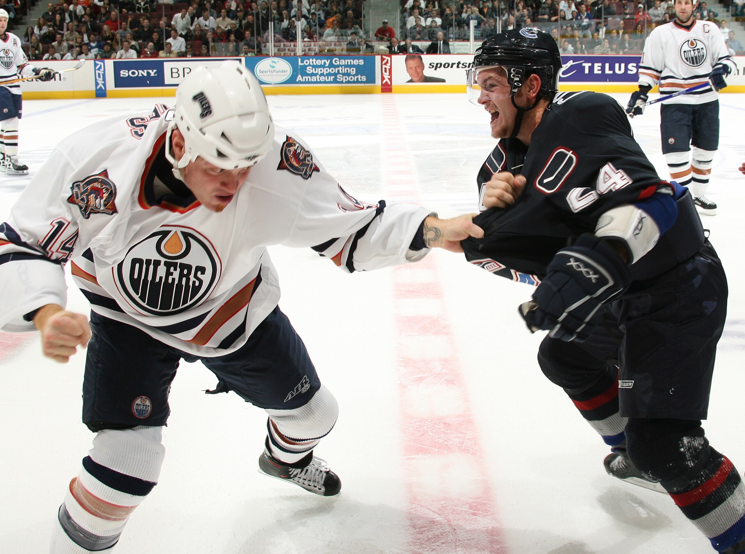 VANCOUVER, CANADA - SEPTEMBER 30:  Matt Cooke #24 of  the Vancouver Canucks has his sweater grabbed by Raffi Torres #14 of the Edmonton Oilers as the two fight during their pre-season game at General Motors Place on September 30, 2006 in Vancouver, Canada