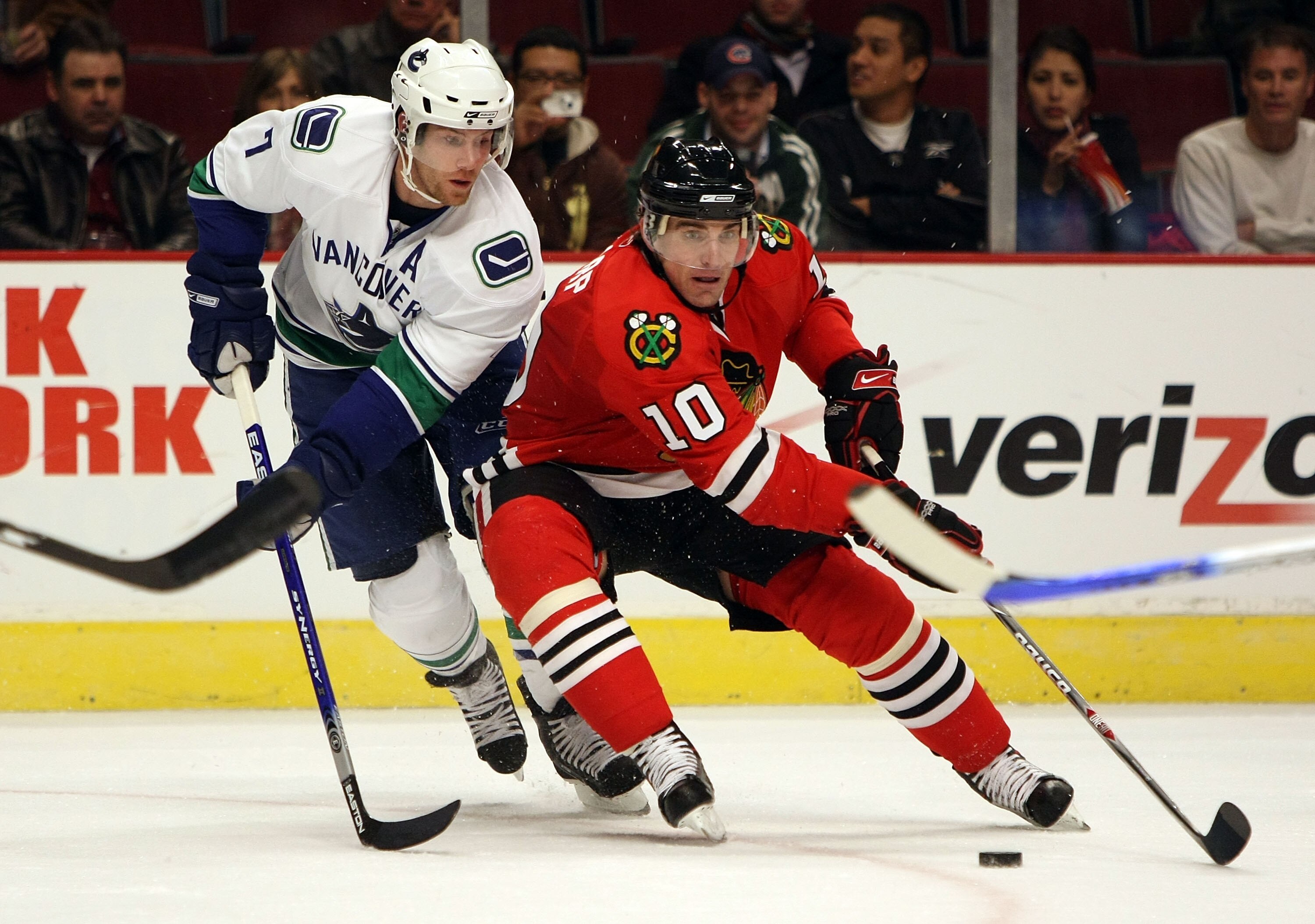CHICAGO - DECEMBER 05:  Patrick Sharp #10 of the Chicago Blackhawks skates with the puck against Brendan Morrison #7 of the Vancouver Canucks at the United Center on December 5, 2007 in Chicago, Illinois.  (Photo by Jonathan Daniel/Getty Images)