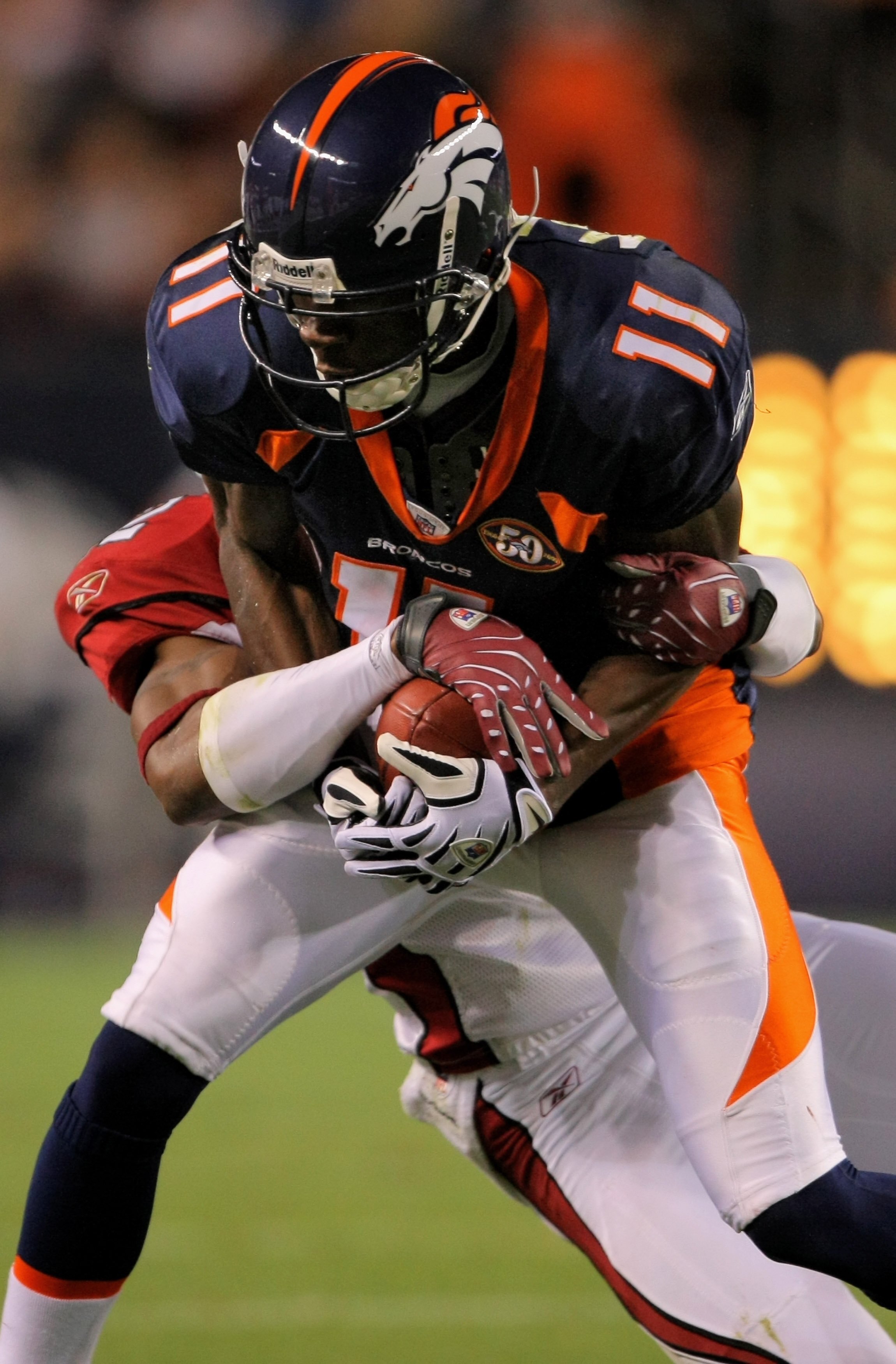 DENVER - SEPTEMBER 03:  Wide receiver Kenny McKinley #11 of the Denver Broncos makes a reception and cornerback Greg Toler #32 of the Arizona Cardinals tries to strip the ball away during preseason NFL action at Invesco Field at Mile High on September 3, 