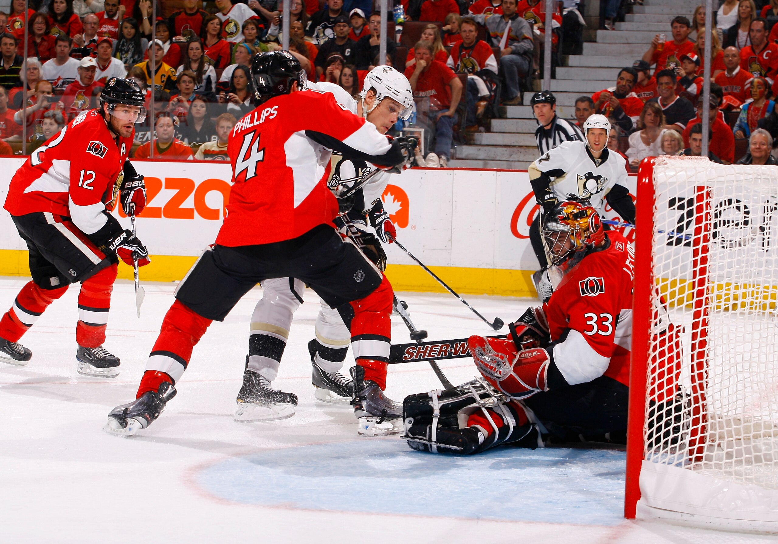 OTTAWA, ON - APRIL 24:  Pascal Leclaire #33 of the Ottawa Senators makes a pad save down low while teammate Chris Phillips #4 tries to tie up Alexei Ponikarovsky #23 of the Pittsburgh Penguins at the top of the crease during Game 6 of the Eastern Conferen