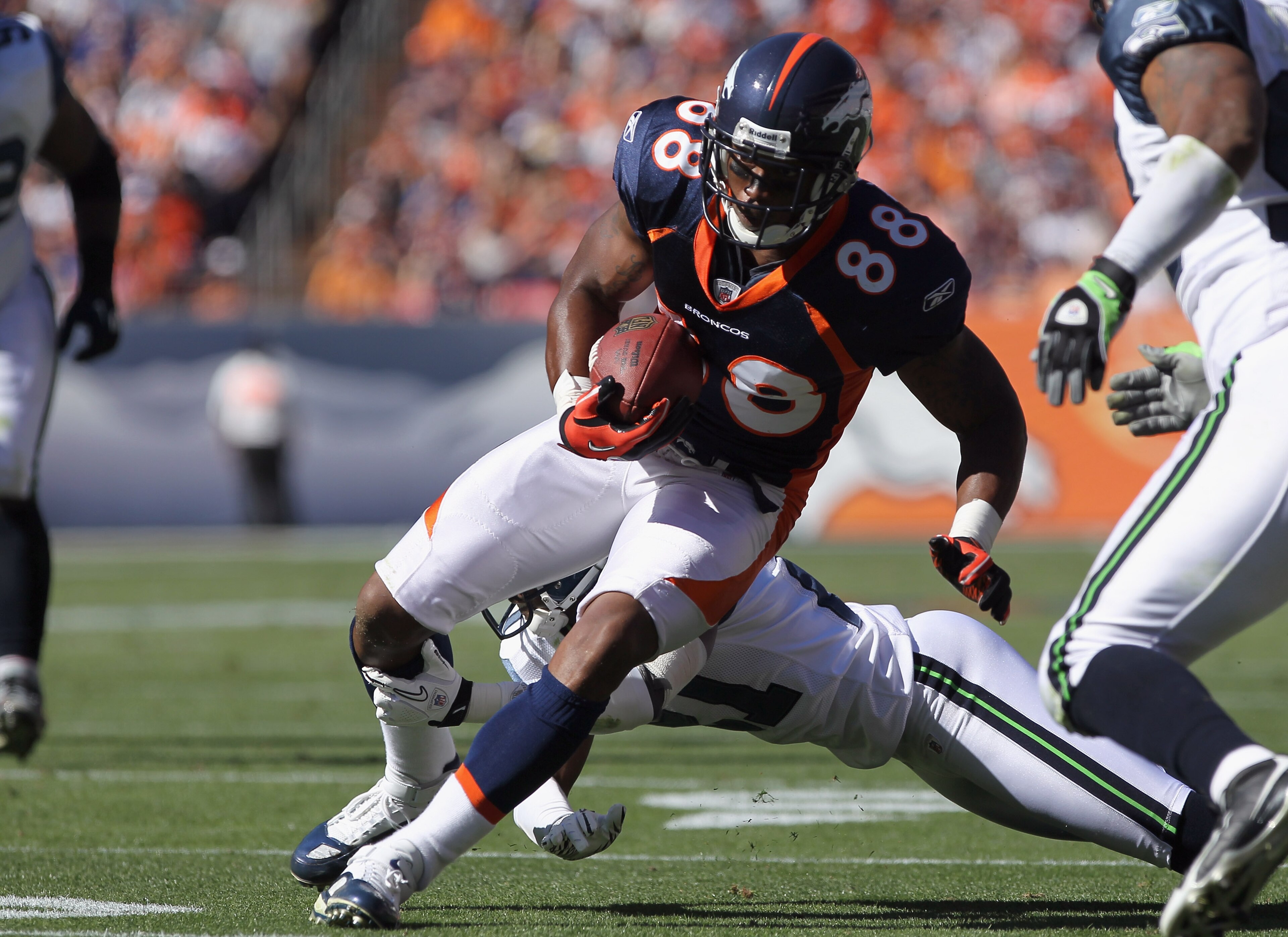 DENVER - SEPTEMBER 19:  Tightend Demaryius Thomas #88 of the Denver Broncos makes a reception as cornerback Kelly Jennings #21 of the Seattle Seahawks tries to make the tackle at INVESCO Field at Mile High on September 19, 2010 in Denver, Colorado. The Br