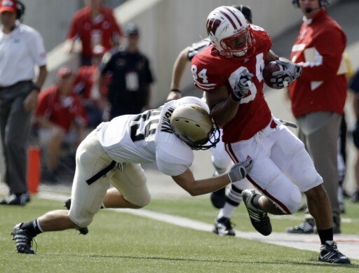 LAS VEGAS - SEPTEMBER 04:  John Clay #32 of the Wisconsin Badgers tries to get away from Deante' Purvis #26 of the UNLV Rebels during the first quarter of their game at Sam Boyd Stadium September 4, 2010 in Las Vegas, Nevada.  (Photo by Ethan Miller/Getty