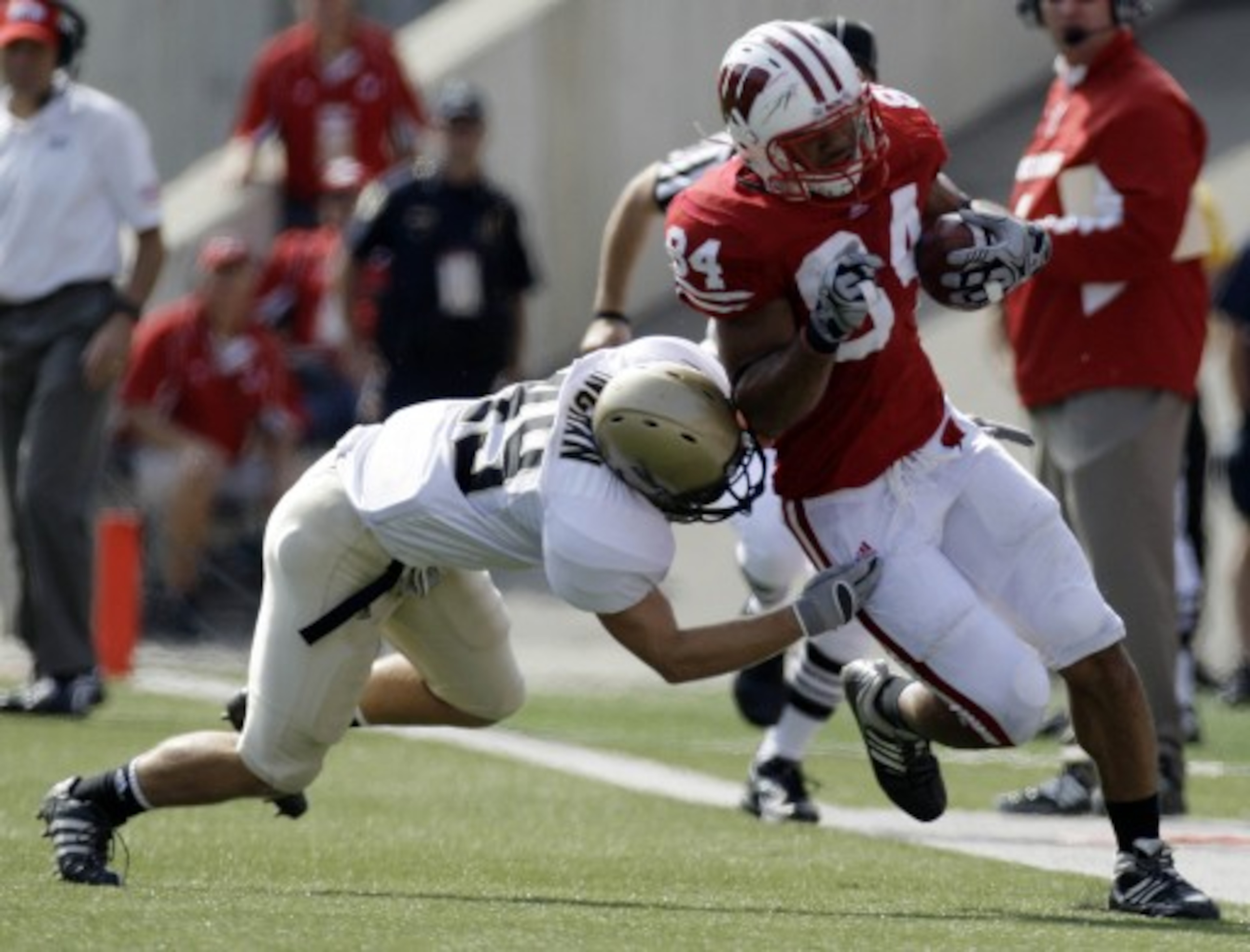 LAS VEGAS - SEPTEMBER 04:  John Clay #32 of the Wisconsin Badgers tries to get away from Deante' Purvis #26 of the UNLV Rebels during the first quarter of their game at Sam Boyd Stadium September 4, 2010 in Las Vegas, Nevada.  (Photo by Ethan Miller/Getty